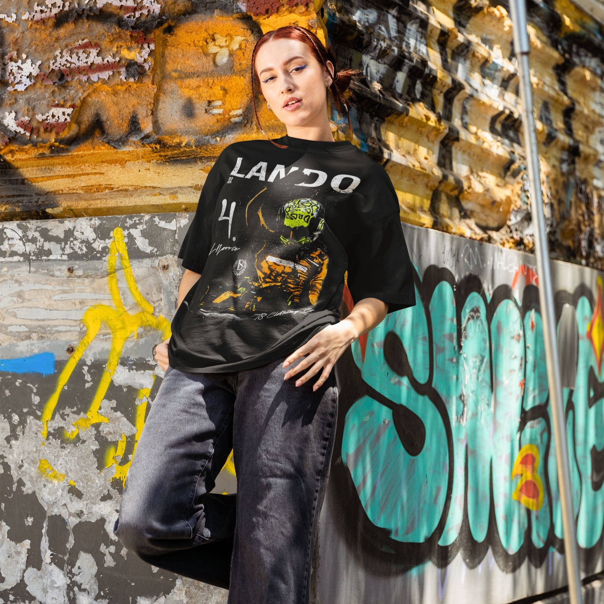 Person wearing a black t-shirt with graphic design in front of a graffiti-covered wall.