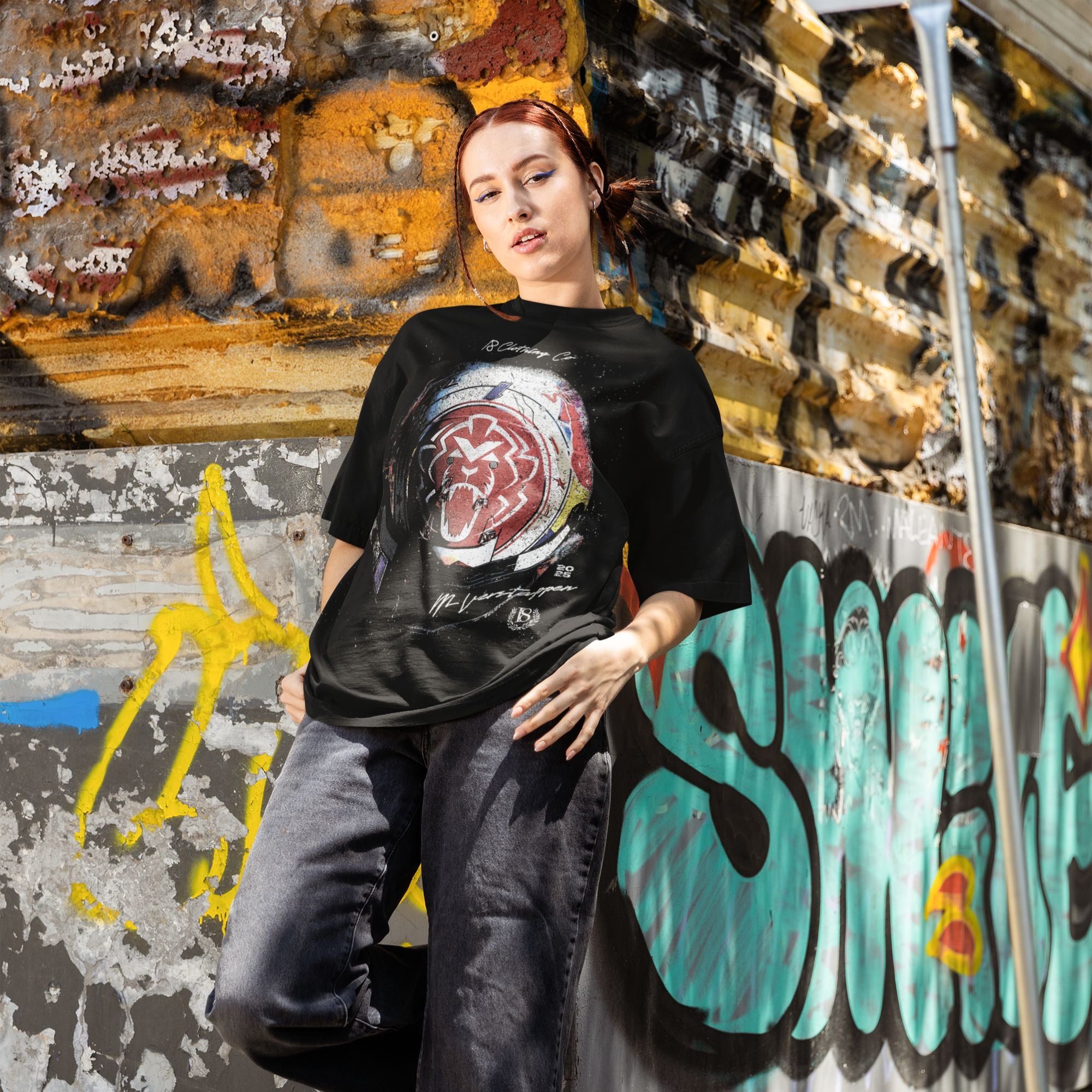 Person wearing a black t-shirt with a graphic design in front of a graffiti-covered wall.