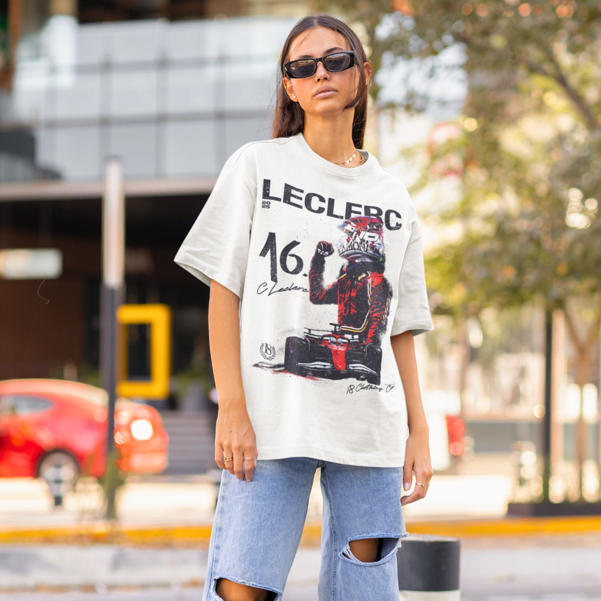 Person wearing a white t-shirt with a graphic design on a city street.