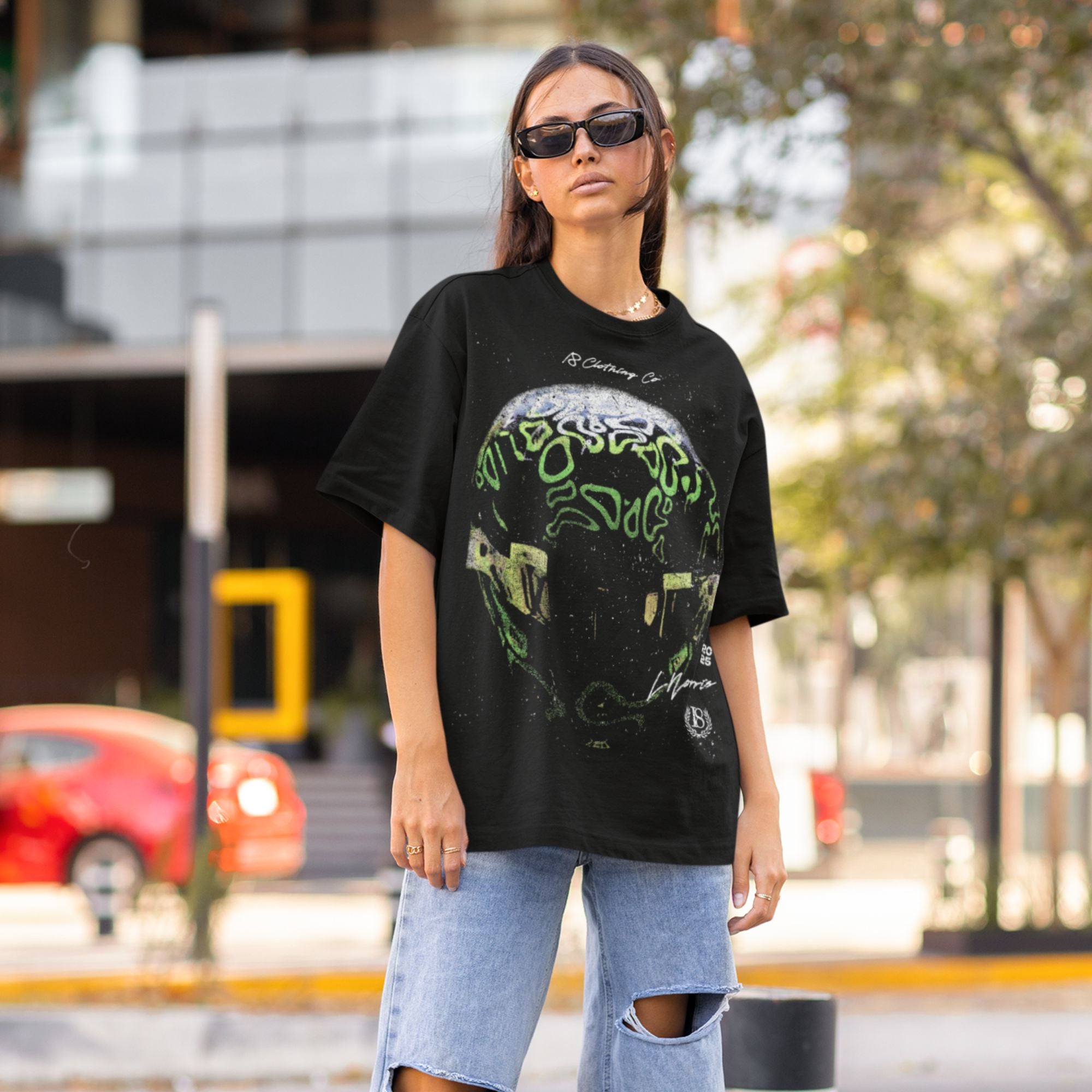 Woman wearing a black t-shirt with a green graphic design outdoors.