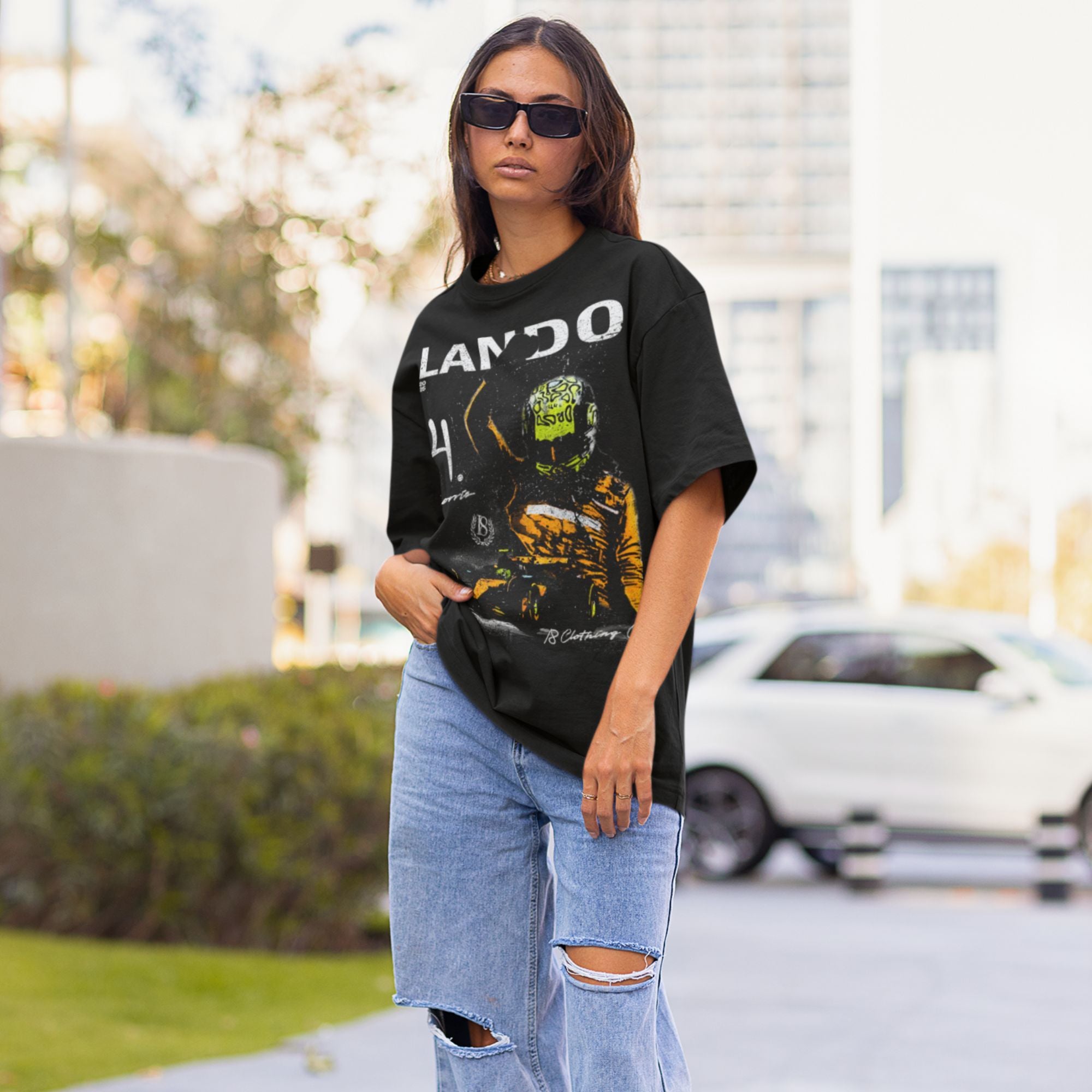 Person wearing a black t-shirt with graphic design and ripped jeans outdoors.
