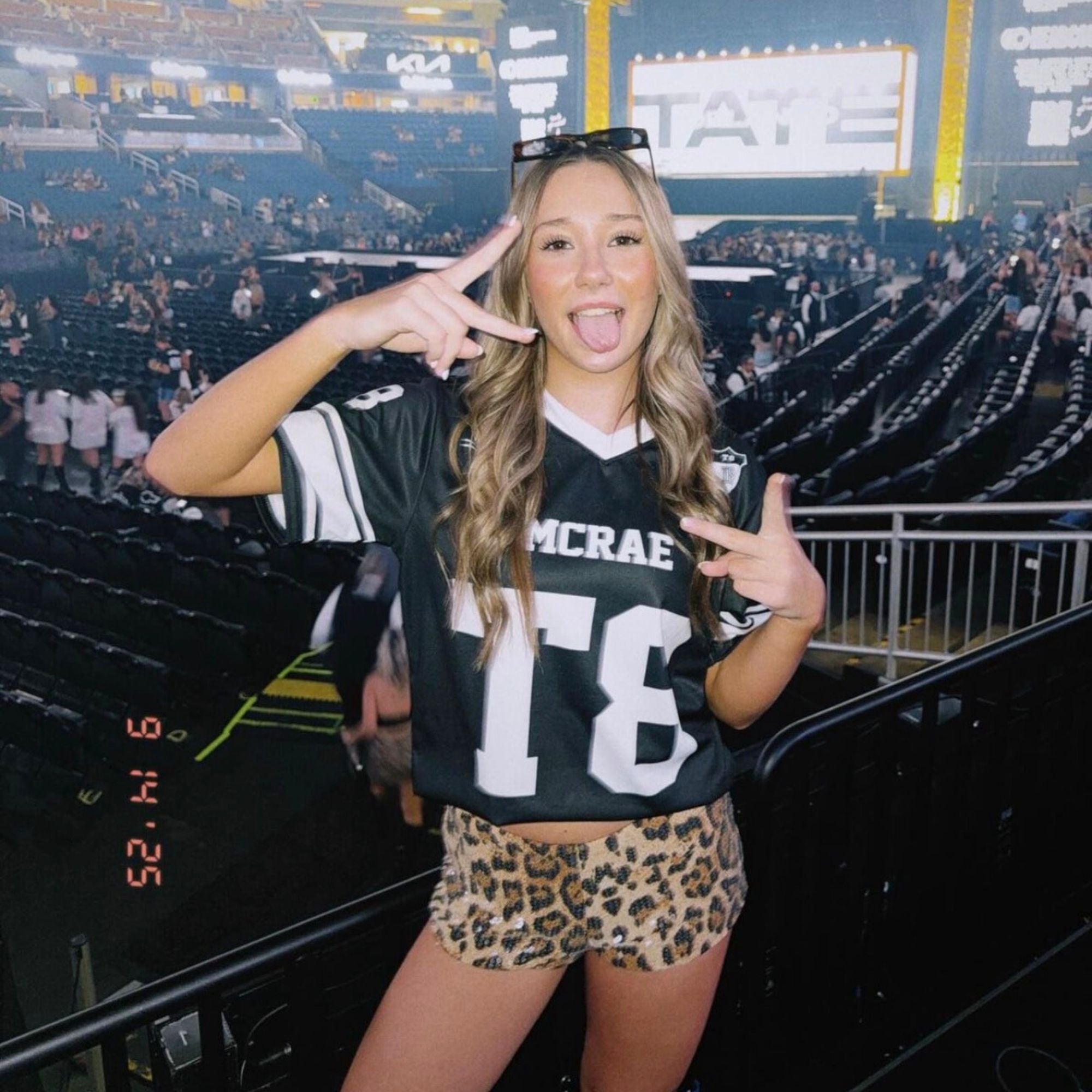 Person wearing a sports jersey and leopard print shorts in a stadium setting