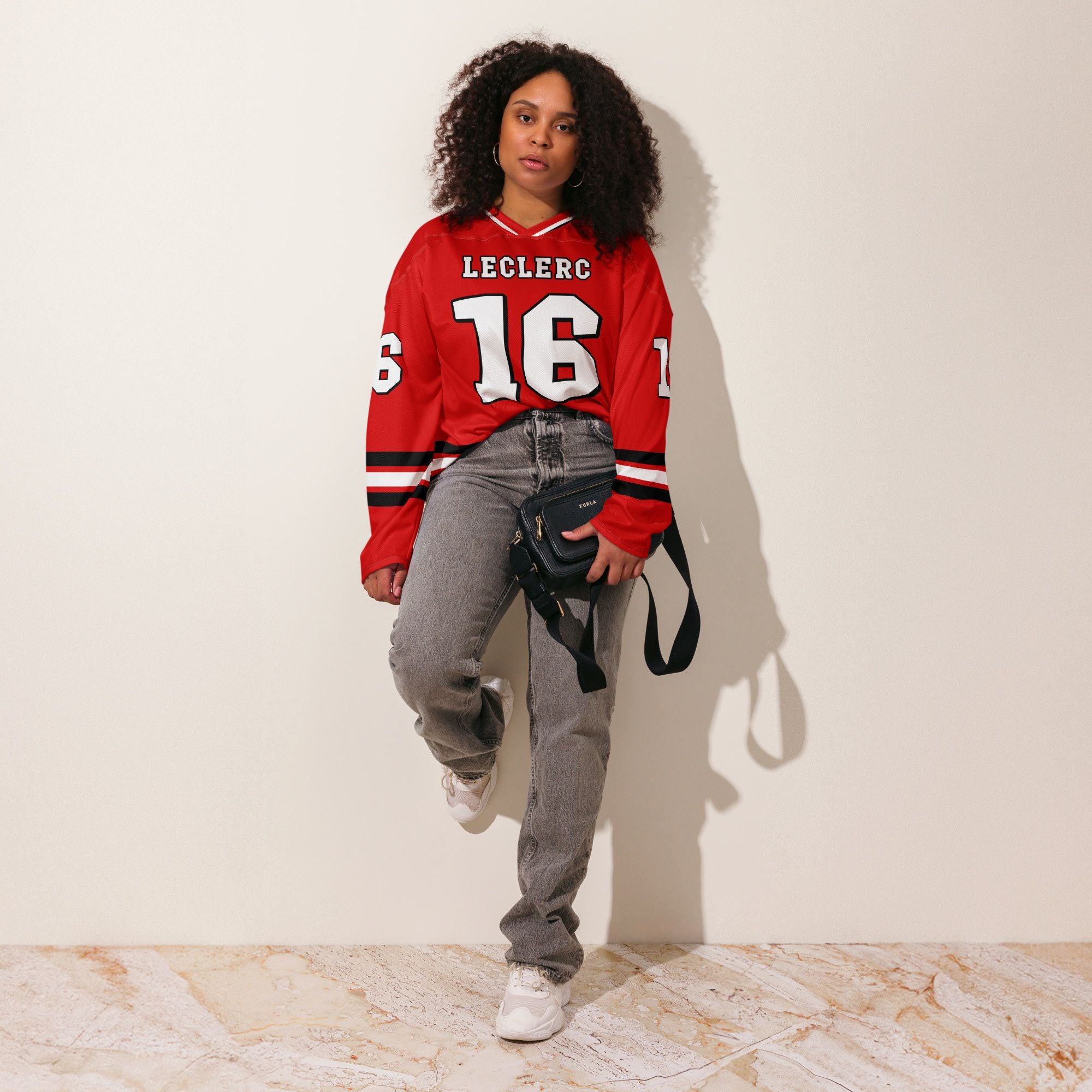 A Ferrari red hockey jersey with charles lecerc's f1 racing number 16 on the front in back, colored in black.