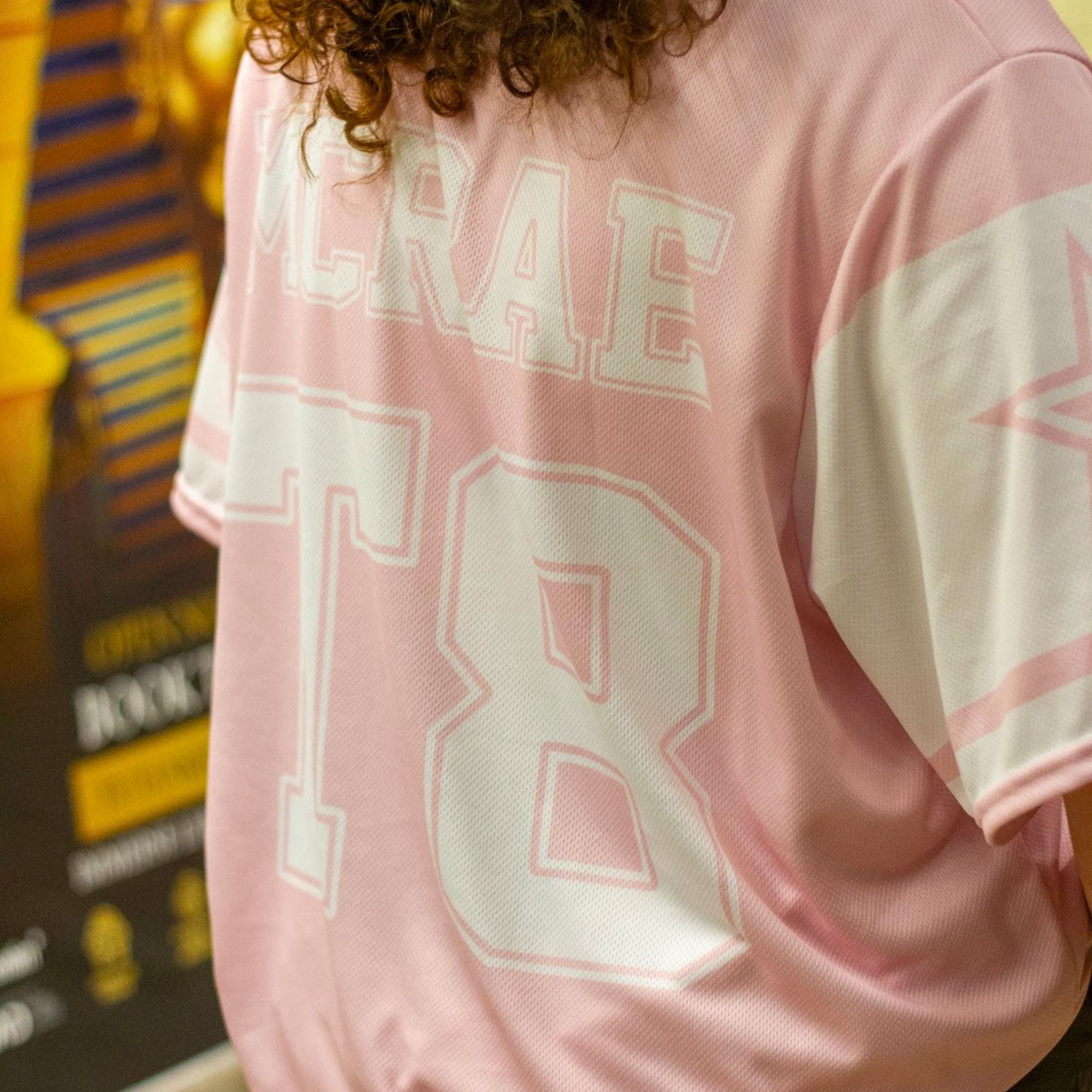 A pink and white football jersey with Tate Mcare on the back and front in white with a white outline.