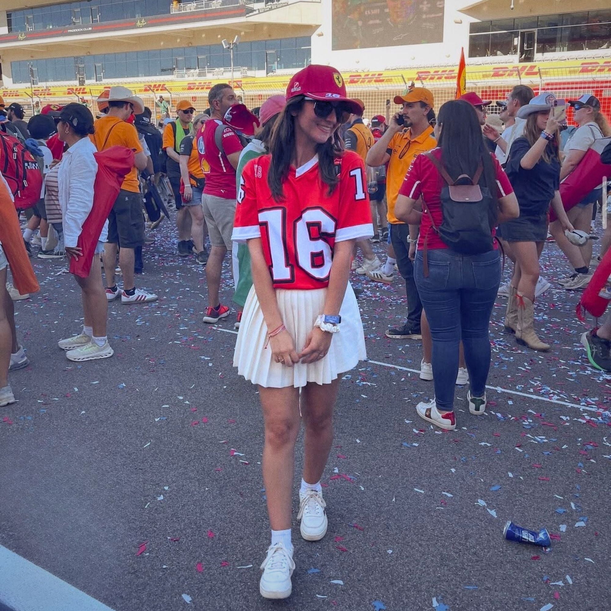 Woman in red and white sports jersey with number 16 at a sports event.