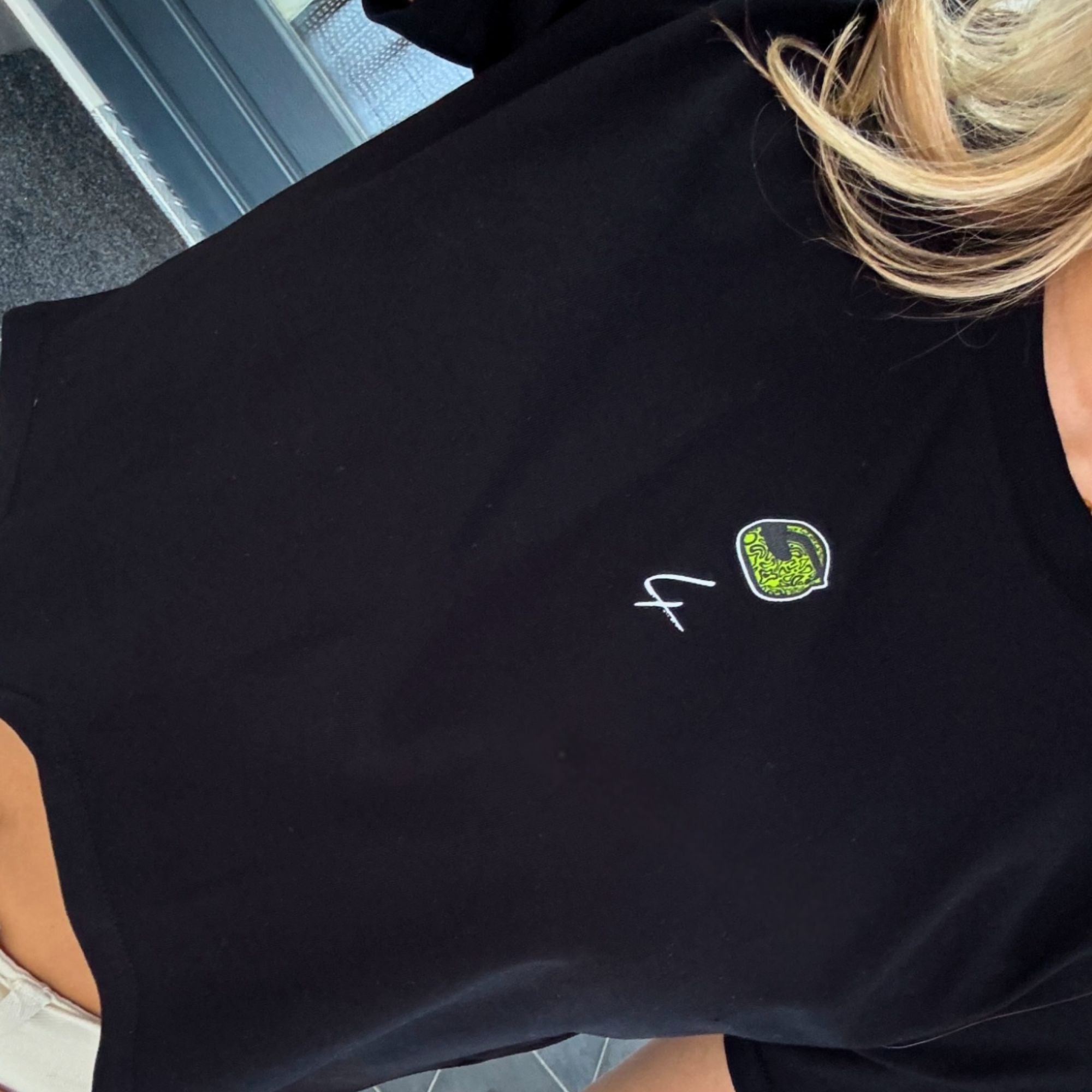 A black crop top with a carton image of Lando Norris's neon green and black helmut, with the number 4 in white below it.