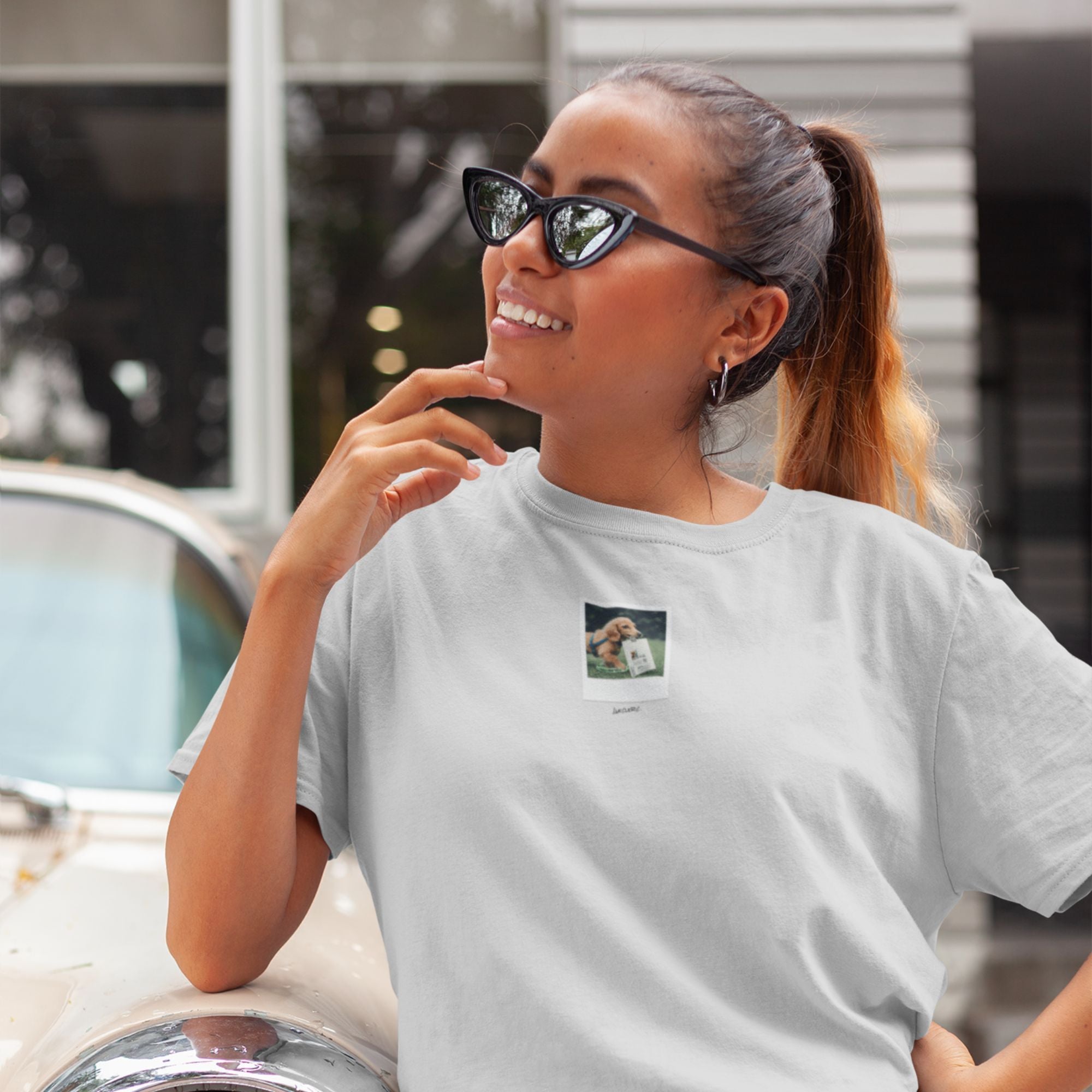 Woman wearing a white t-shirt with a small graphic on it, sitting outdoors.