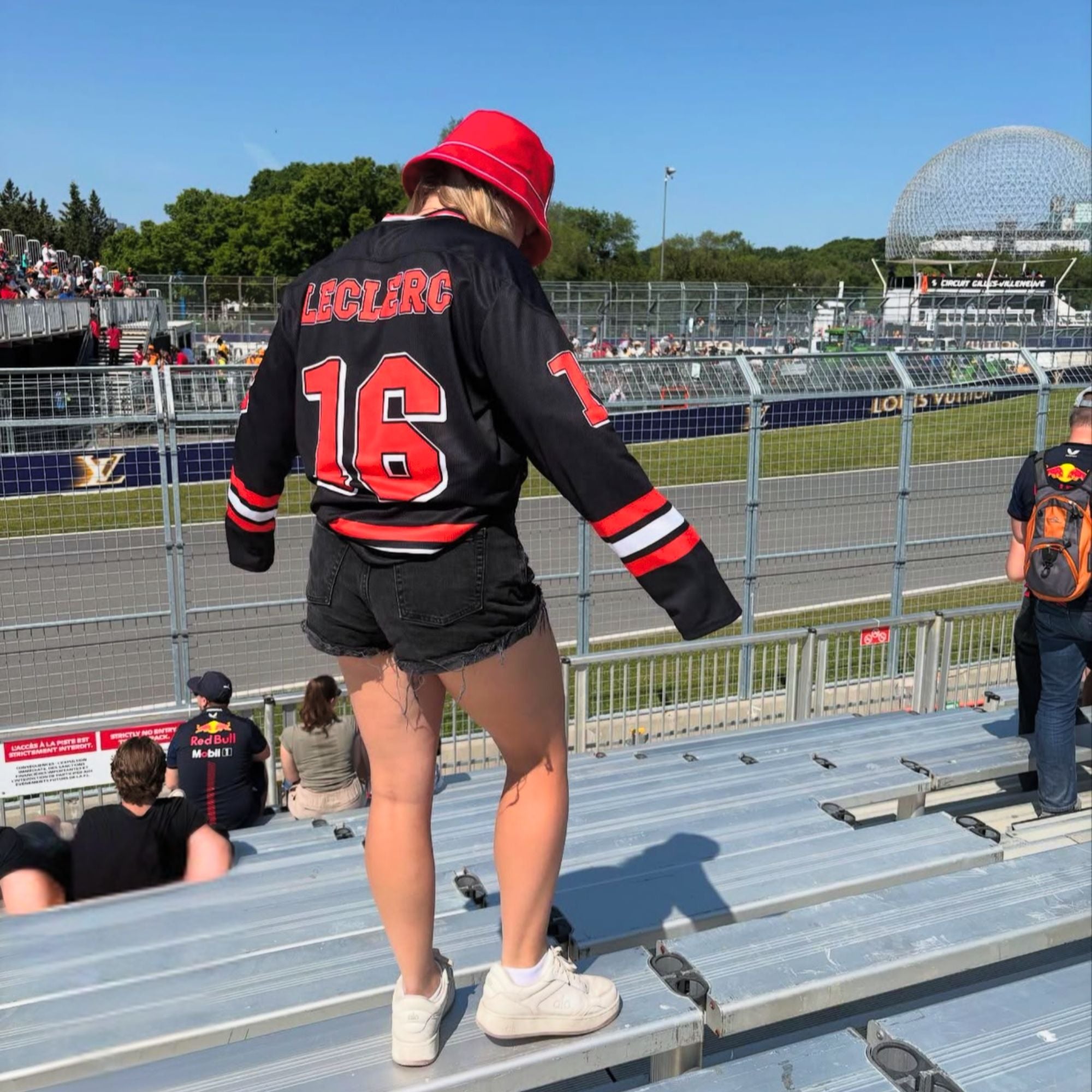 A black hockey jersey with red and white stripes on the bottom and the arms. It has Charles Leclerc's Ferrari F1 racing number 16 on the front and the back with the name Leclerc just above each number