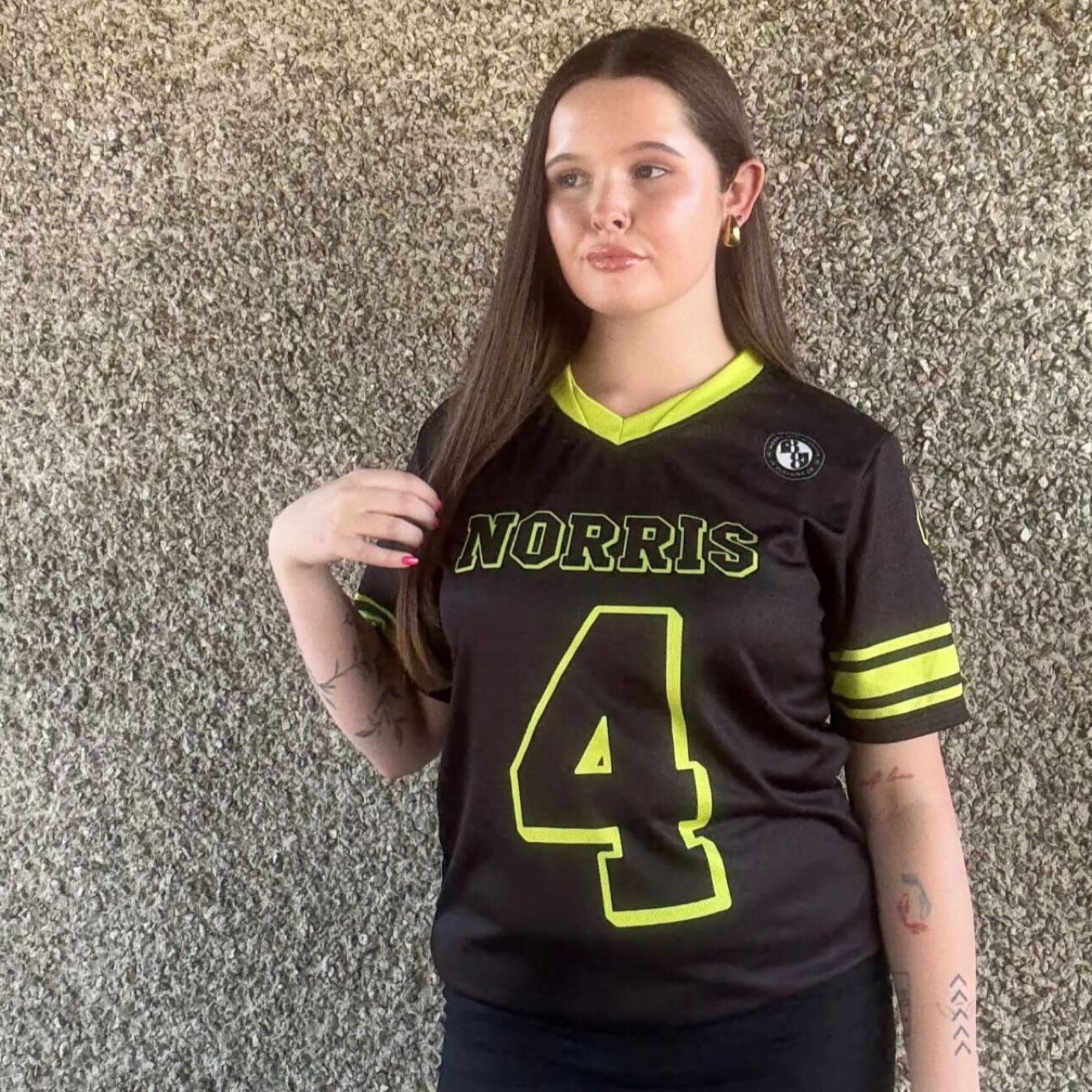 Person wearing a black sports jersey with 'Norris' and number '4' against a textured wall.