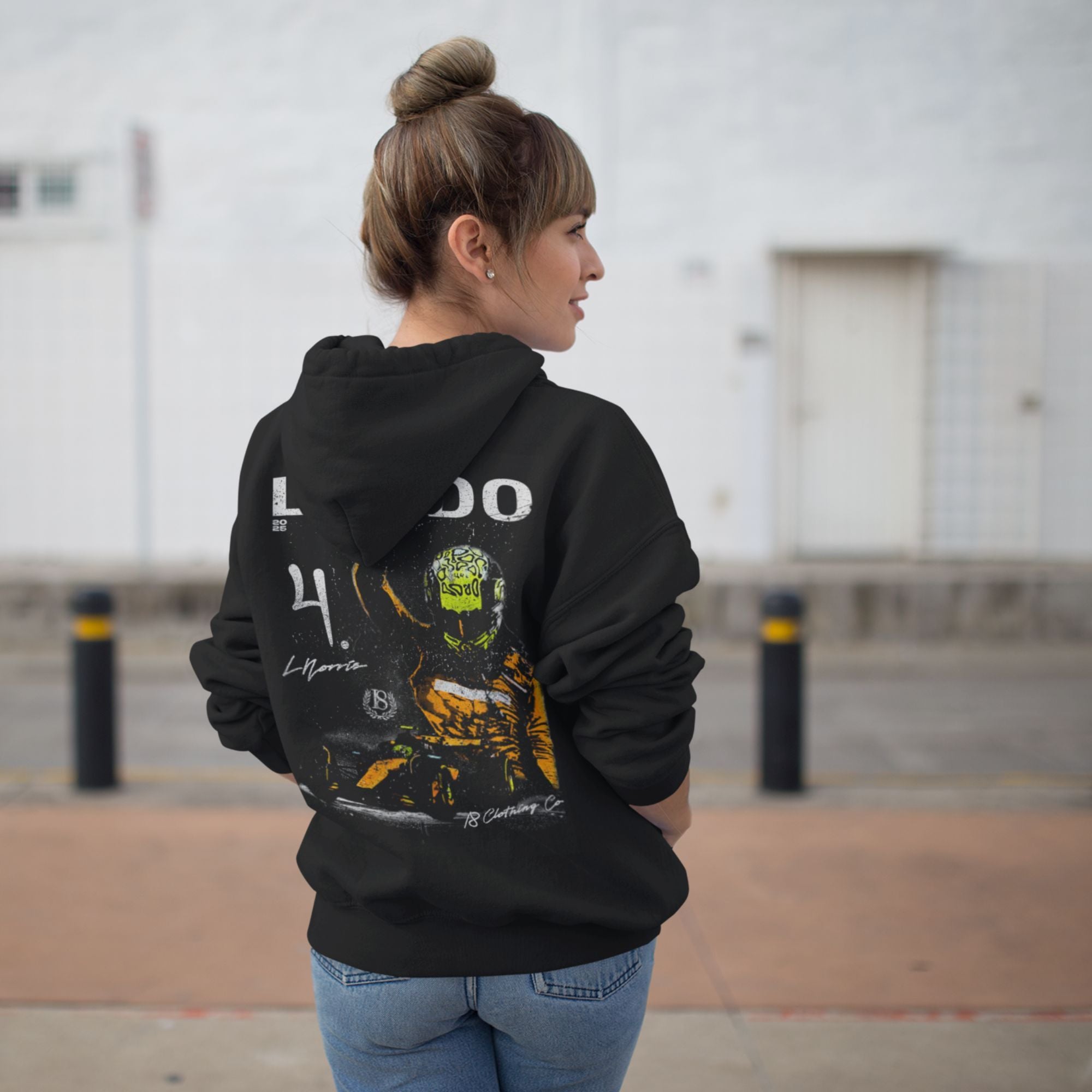 Person wearing a black hoodie with a graphic design on the back, standing outdoors.