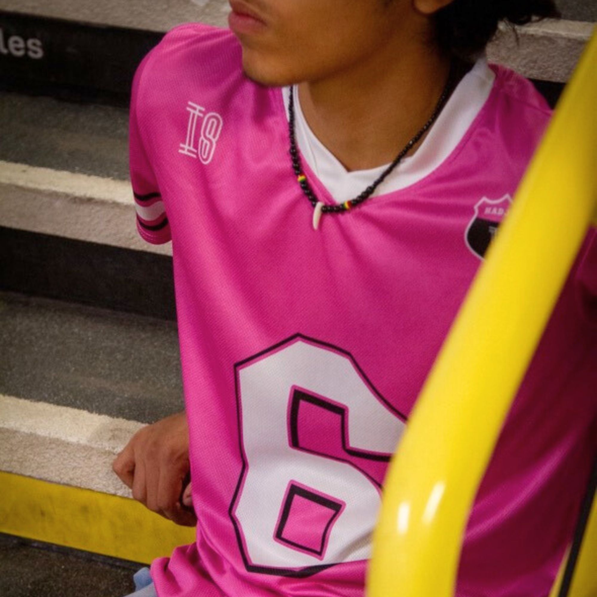 Person wearing a pink sports jersey with number 18 and letter 'B' on a yellow and gray background.