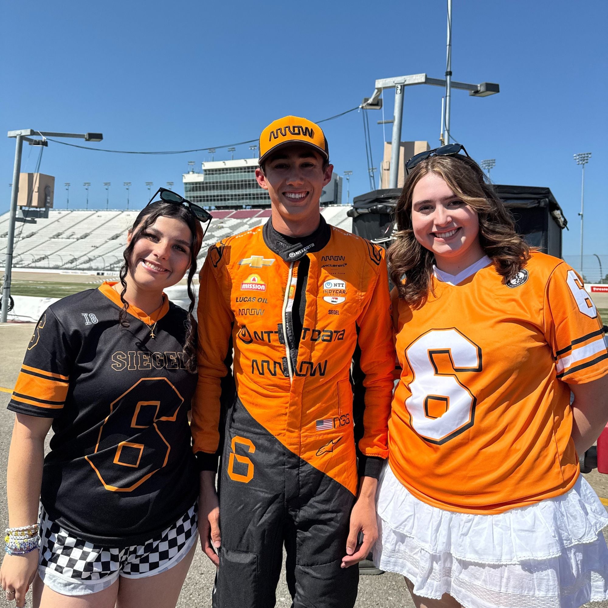 Three people wearing orange and black sports jerseys with the number 6 at a sports event.