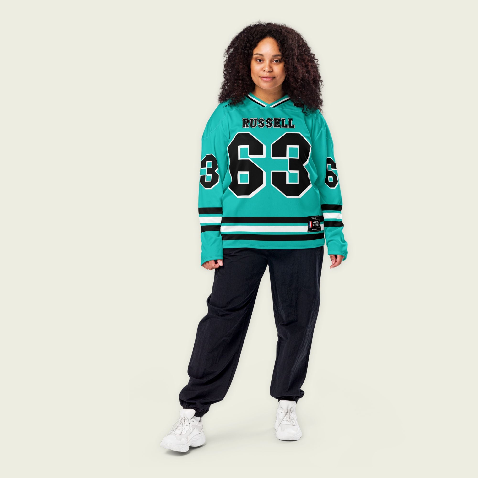 A green hockey jersey with three stipes on the bottom the middle one is white and the bottom and top are black. It has the number 63 that George Russell races with in F1 that is filled with black and a white outline, it is displayed on the back and front. Also there is text on the front and back "Russell"