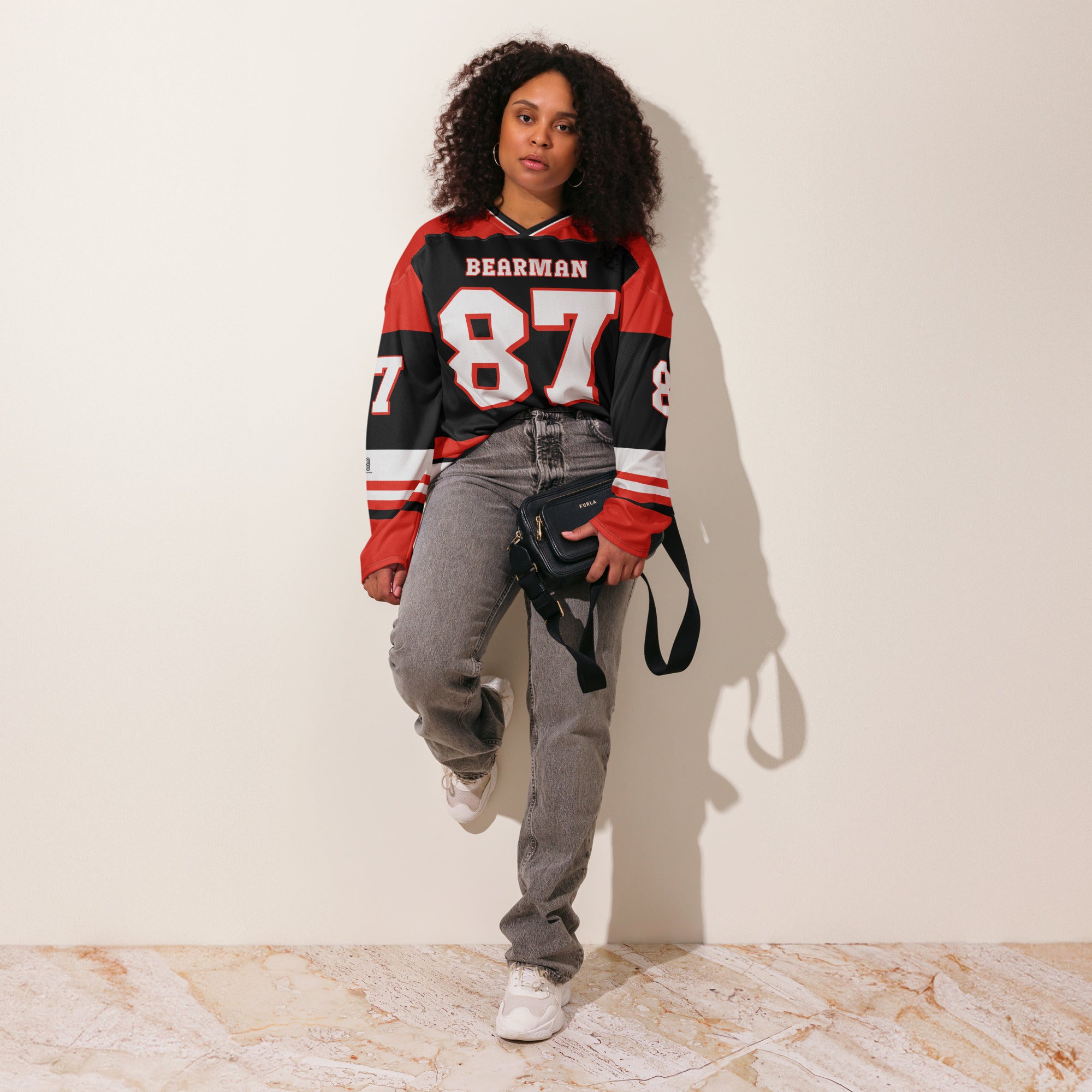 A red and black hockey jersey with Oliver Bearman's Haas F1 racing number 87 on the front and back in white, also the name Bearman is on the back and front in White.