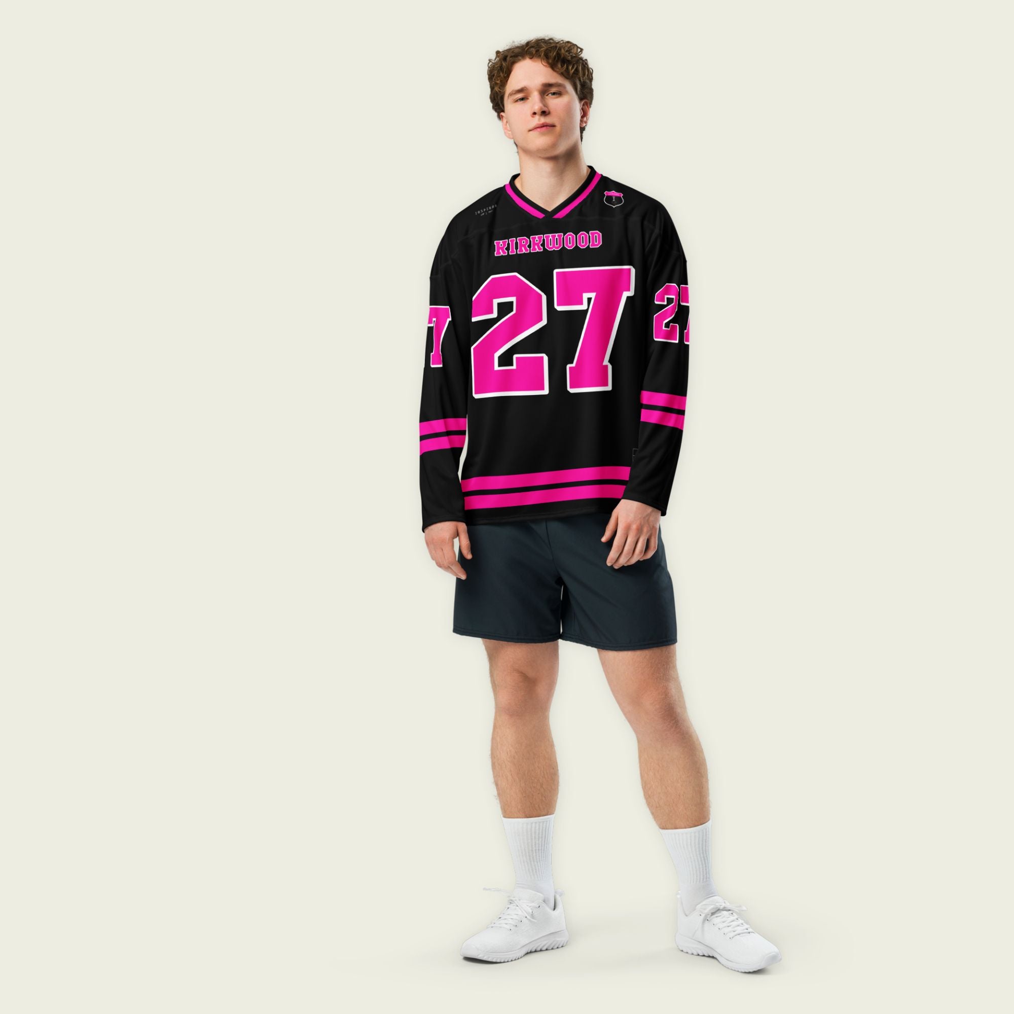 A black hockey jersey with pink stripes on the bottom and the armes, with Kyle Kirkwood's indycar racing number 27 on the arms, back, and front. The jersey also has the name kirkwood displayed on the front and back.