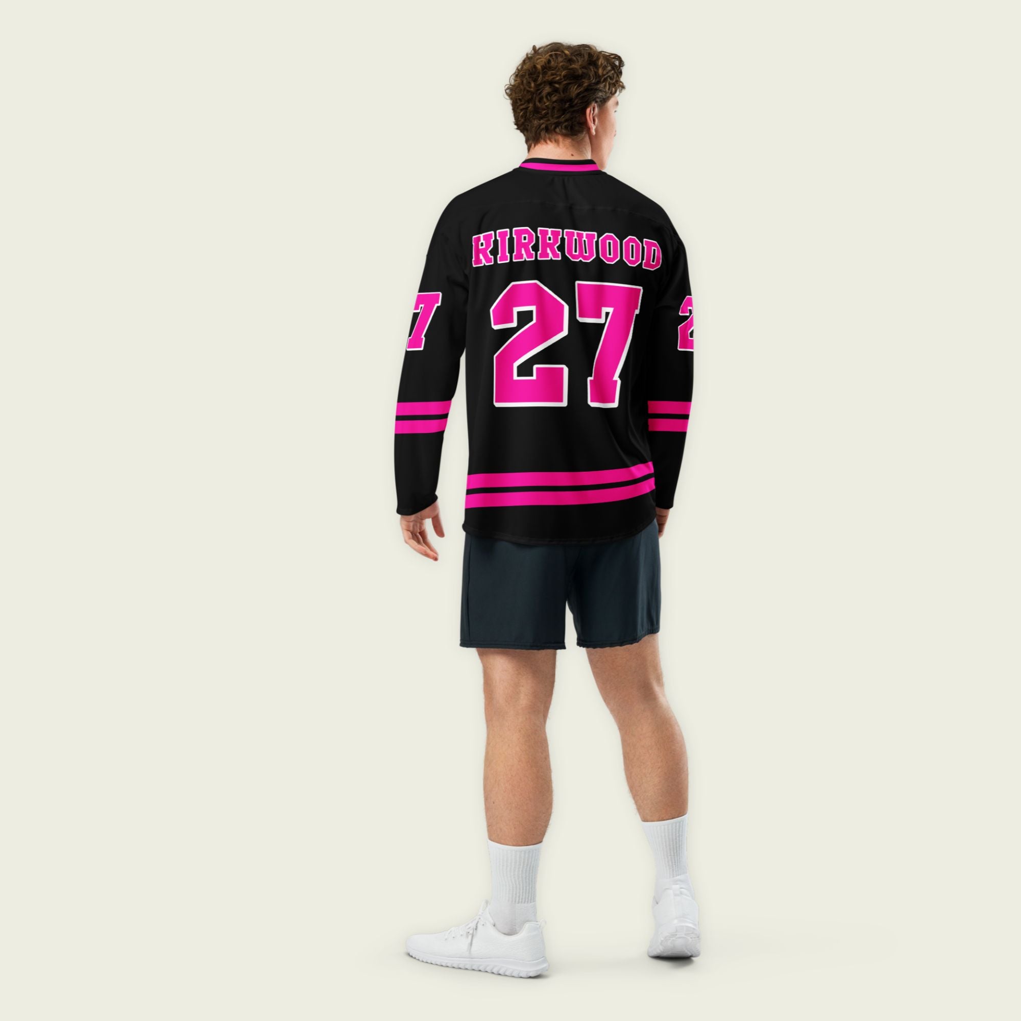 A black hockey jersey with pink stripes on the bottom and the armes, with Kyle Kirkwood's indycar racing number 27 on the arms, back, and front. The jersey also has the name kirkwood displayed on the front and back.