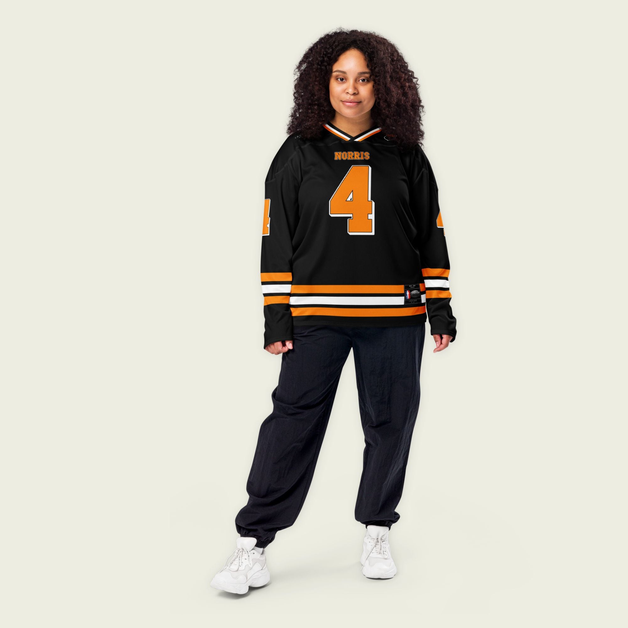 A black hockey jersey with lando norris's mclaren F1 racing number 4 on the front and the black. it has oragne stripesin the top, bottom, and arms. WIth his last name norris on the front and back.