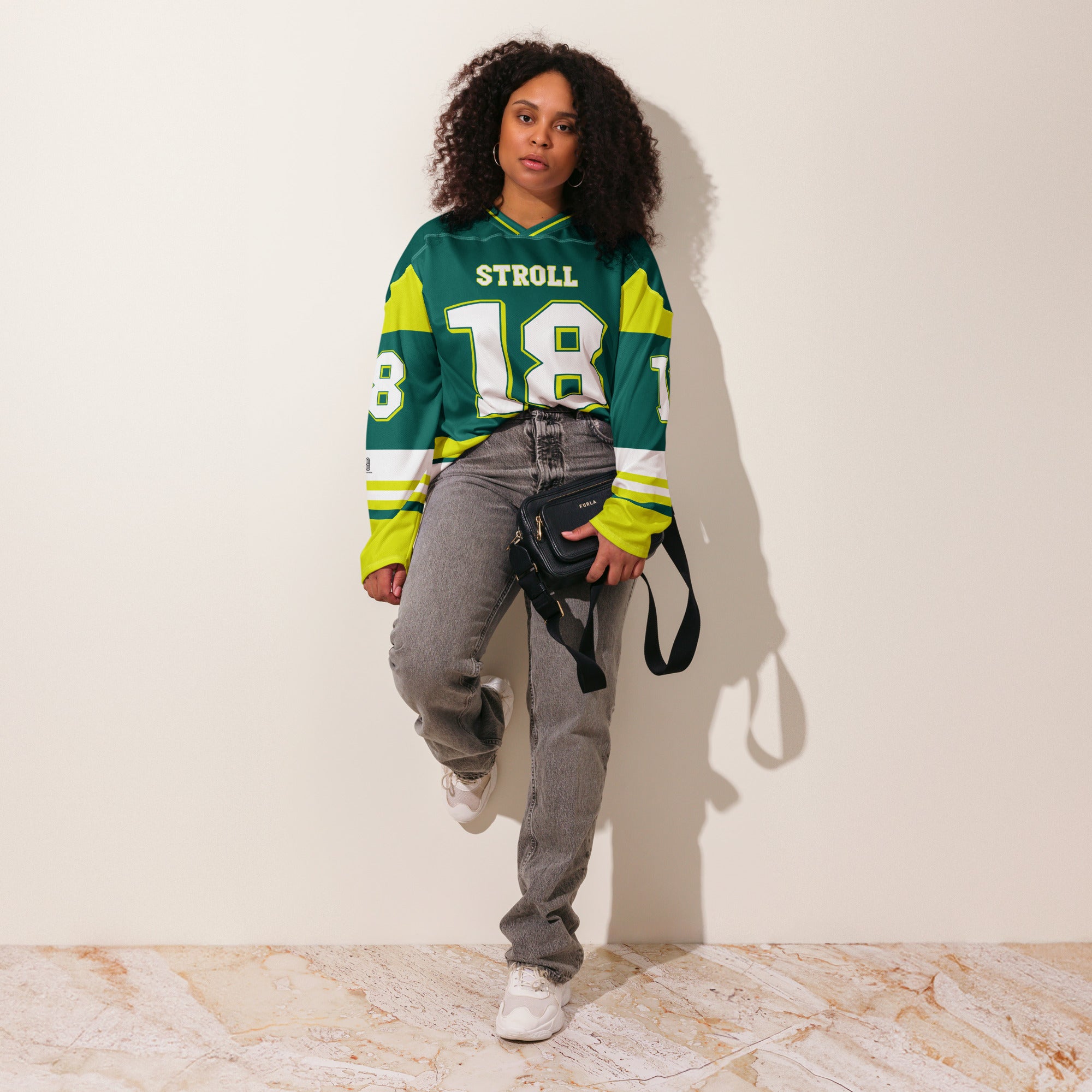 A british green hockey jersey with Lance Stroll's Aston Martin F1 racing number 18 in white on the front and back. It has the name Stroll on the back and front in white as well.