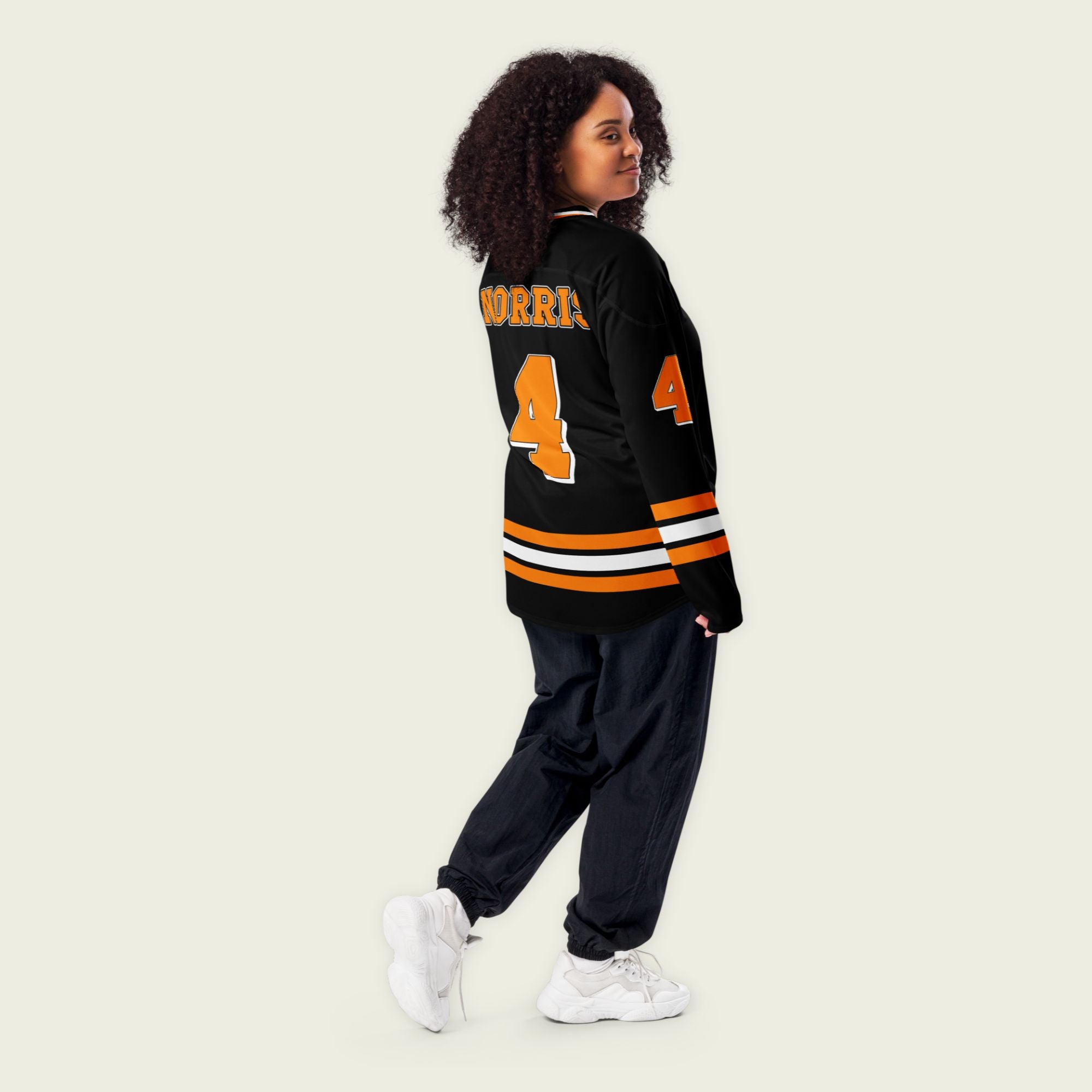 A black hockey jersey with lando norris's mclaren F1 racing number 4 on the front and the black. it has oragne stripesin the top, bottom, and arms. WIth his last name norris on the front and back.