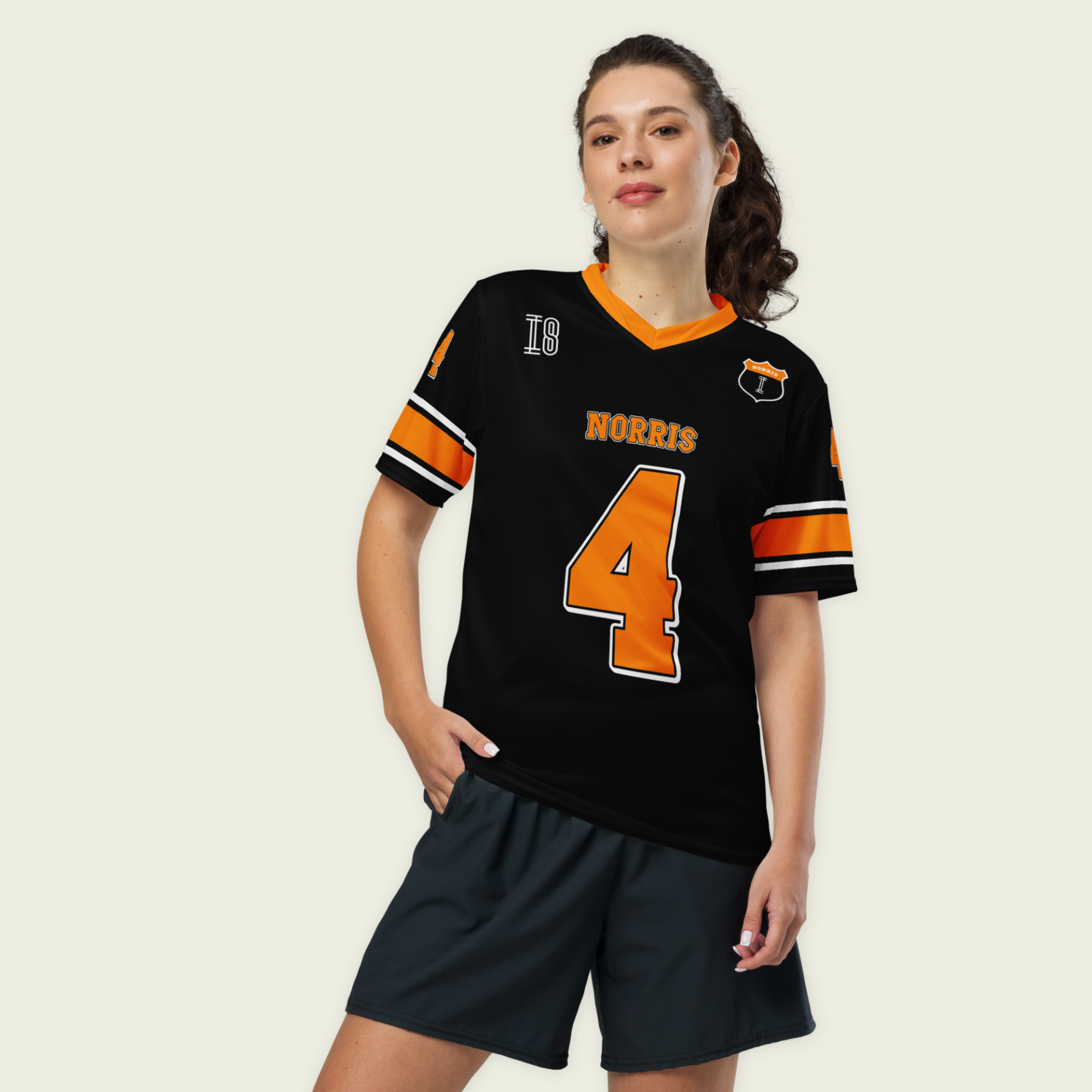 A black and Papaya orange football jersey with Lando Norris's McLaren F1 racing number 4 on the back and front in orange. It has the name Norris in papaya on the front and back as well.