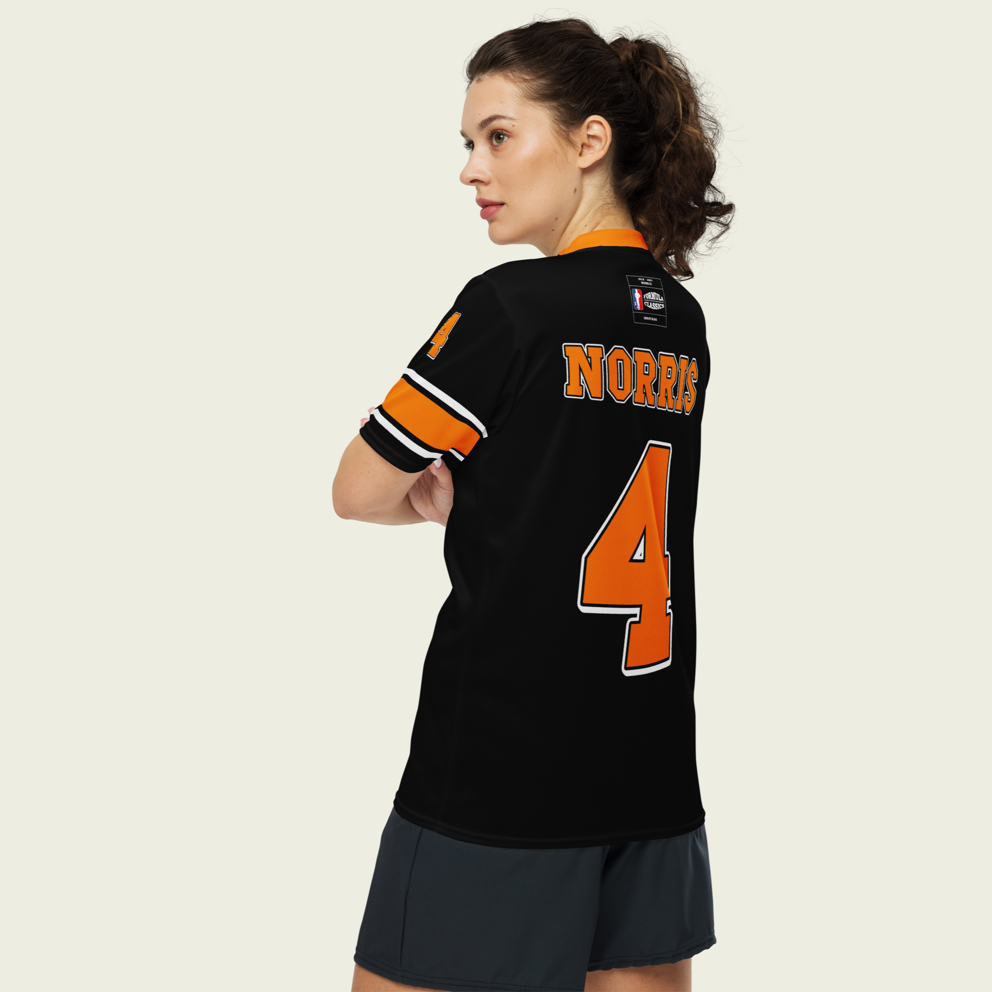 A black and Papaya orange football jersey with Lando Norris's McLaren F1 racing number 4 on the back and front in orange. It has the name Norris in papaya on the front and back as well.