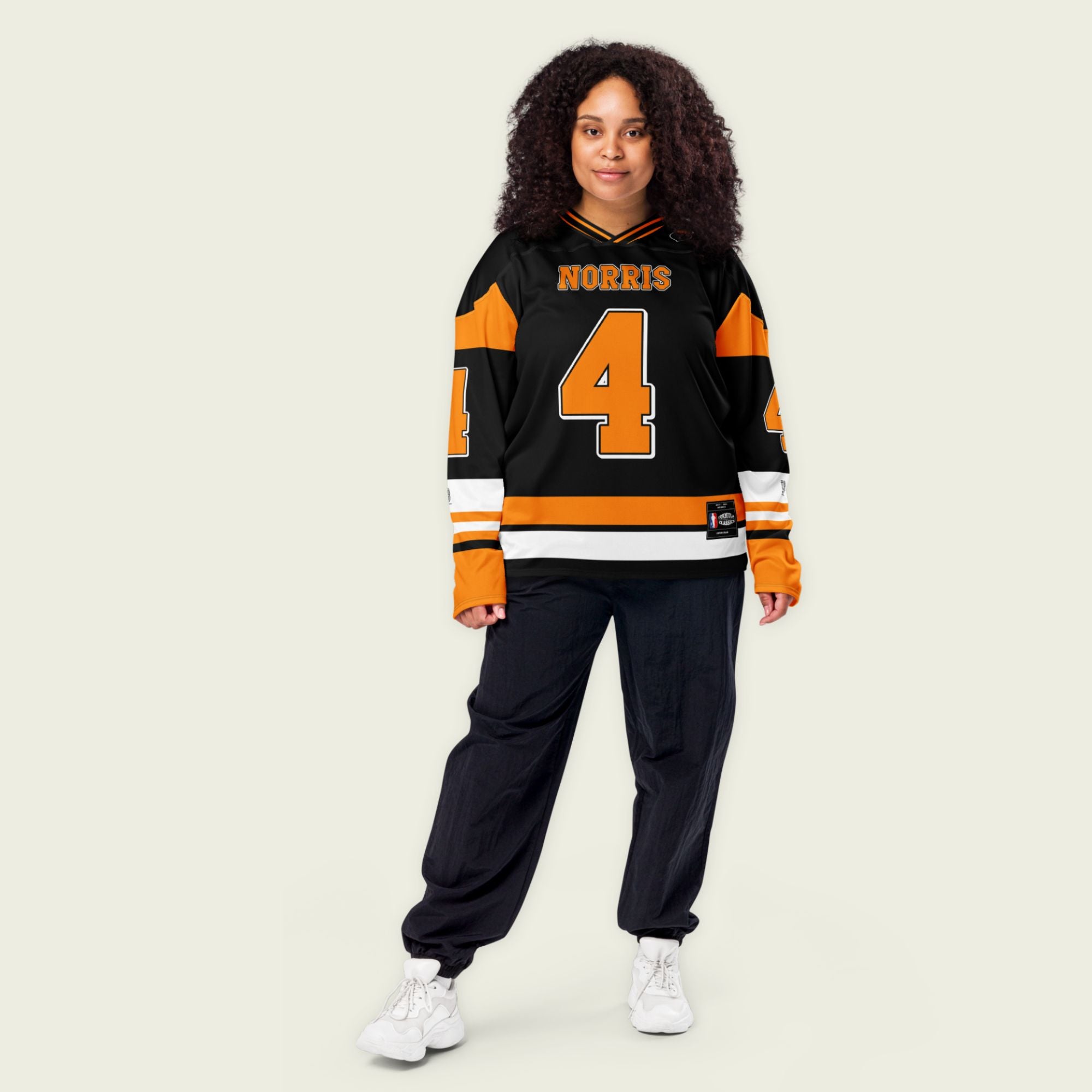 A black hockey jersey with Lando Norris mclaren F1 racing number 4 on the front and back in papaya orange, also the name norris is on the back and front in orange
