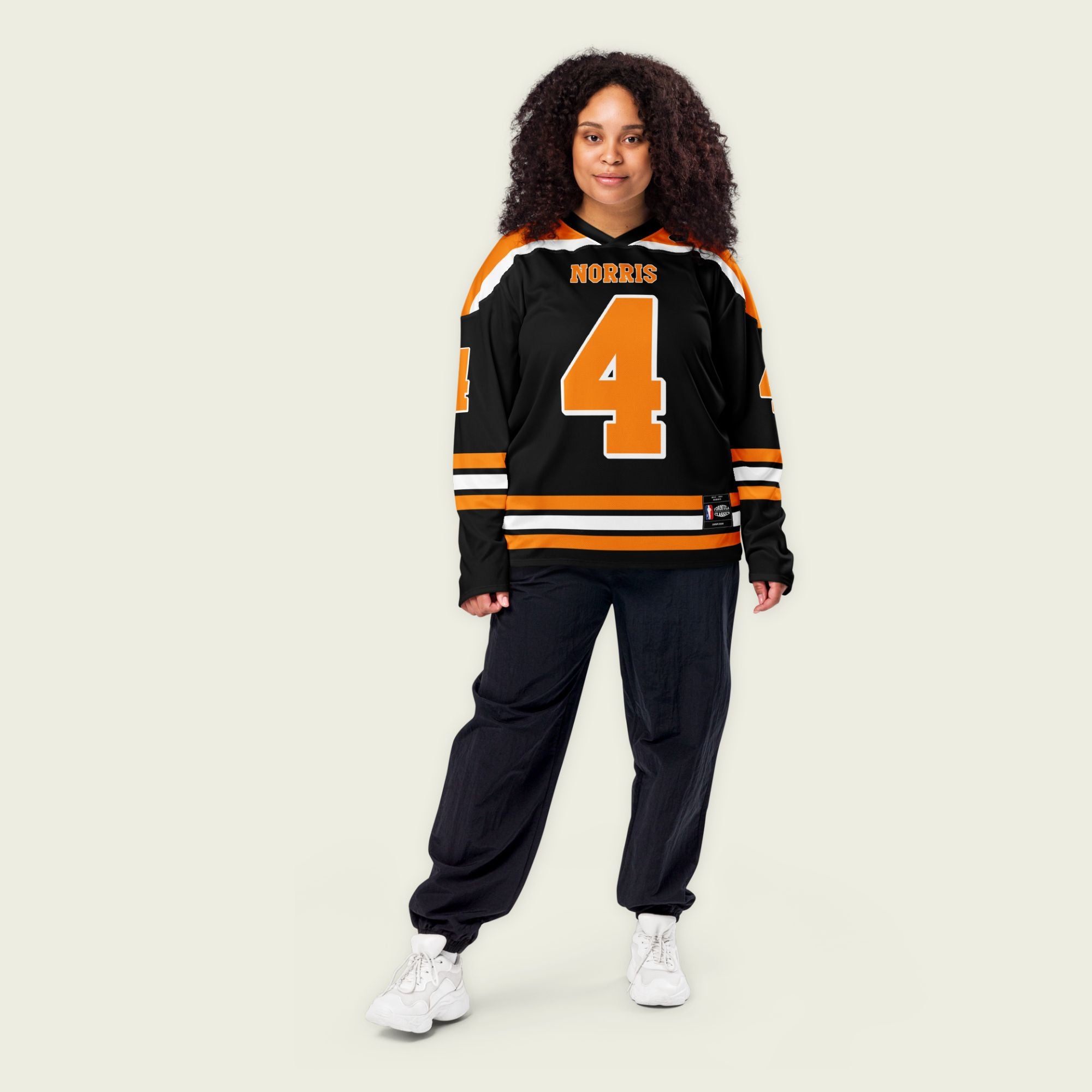 A black hockey jersey with lando norris's mclaren F1 racing number 4 on the front and the black. it has oragne stripesin the top, bottom, and arms. WIth his last name norris on the front and back.