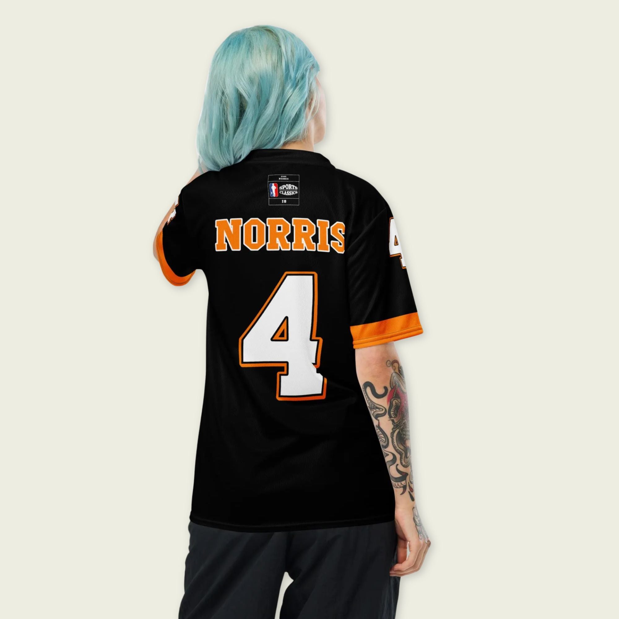 A black and papaya orange football jersey with Lando Norris's McLaren F1 racing number 4 on the back and front in white. It has the name Norris in orange on the front as well.
