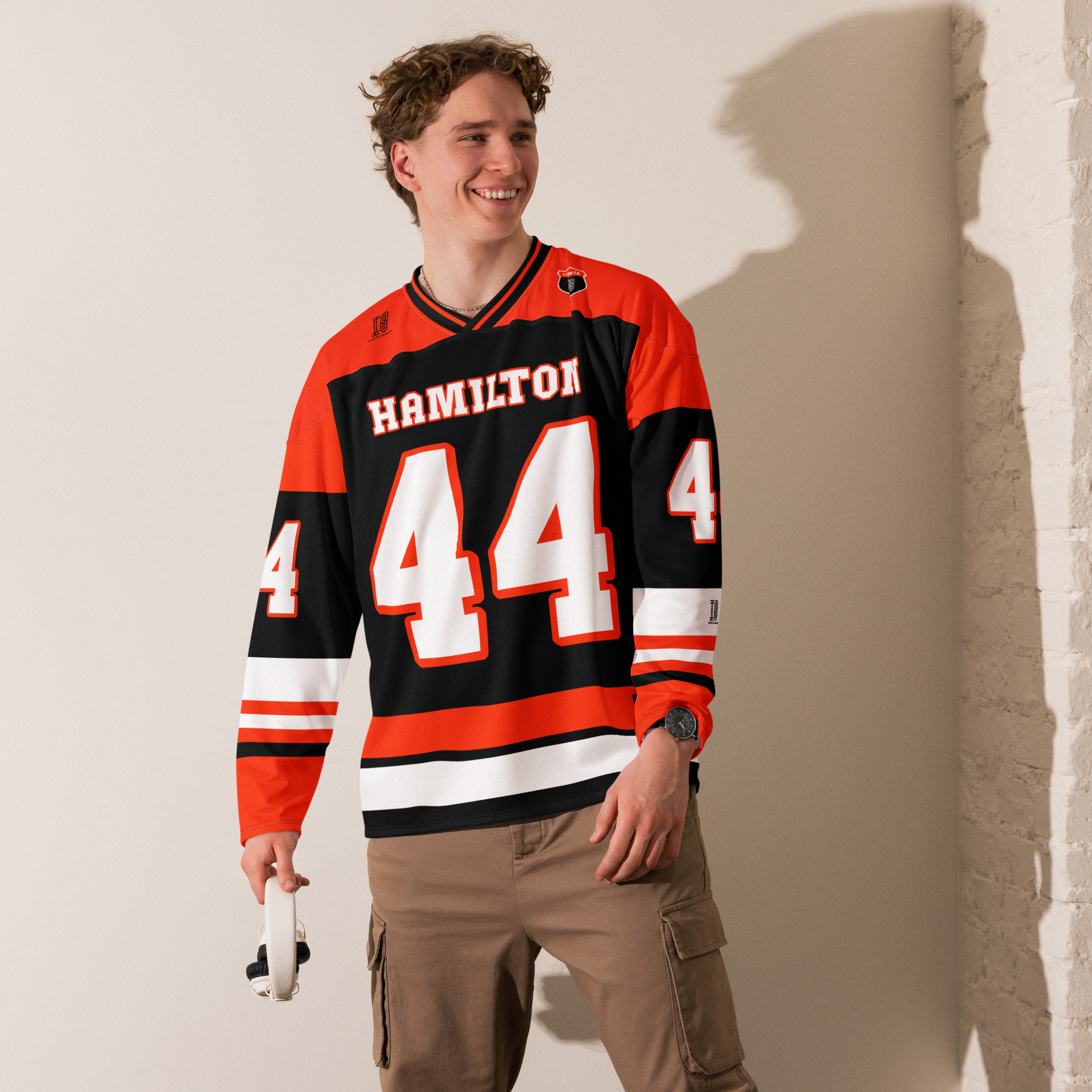 A red and black hockey jersey with Lewis Hamilton's F1 racing number 44 in white on the front and back. It has the name Hamilton on the back and front in white as well.