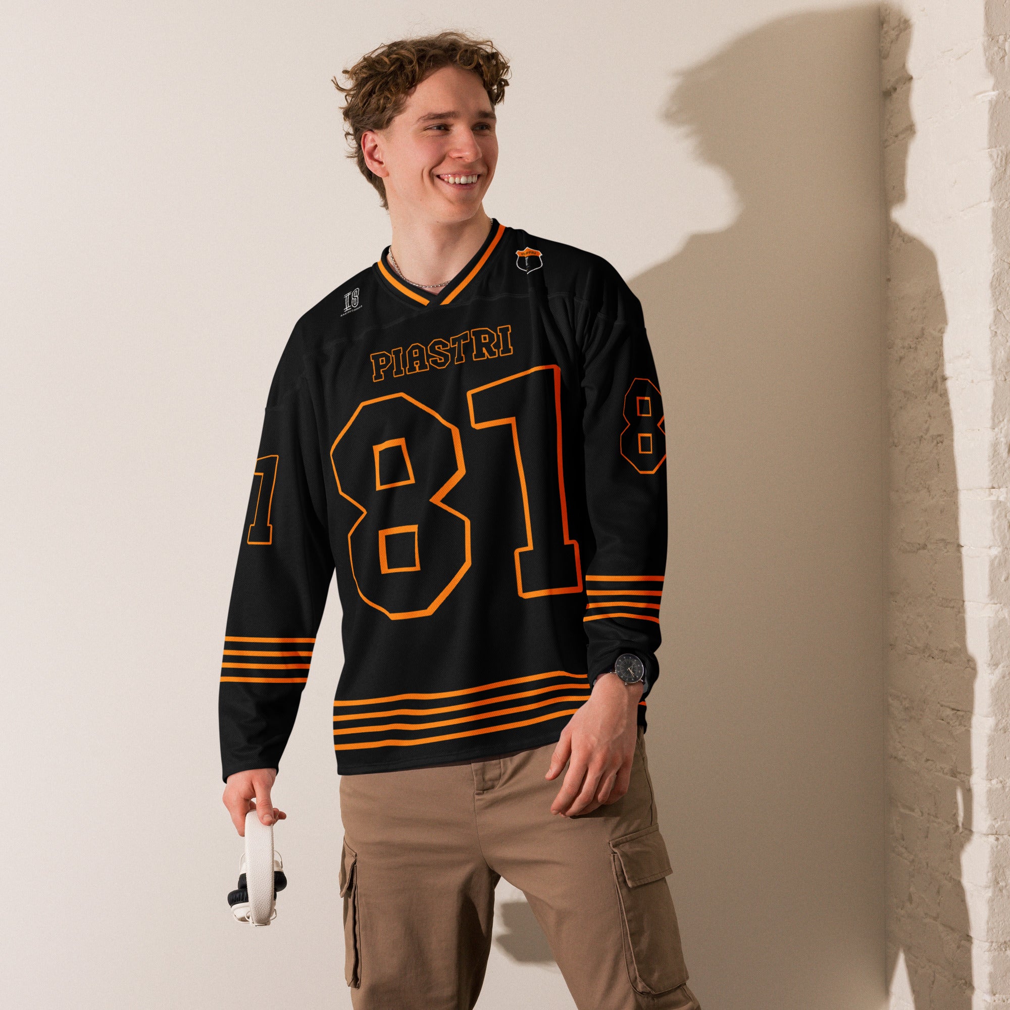 A black ands papaya orange hockey jersey with Oscar Piastri's McLaren F1 racing number 83 in Orange on the front and back. It has the name Piastri the back and front in Orange as well