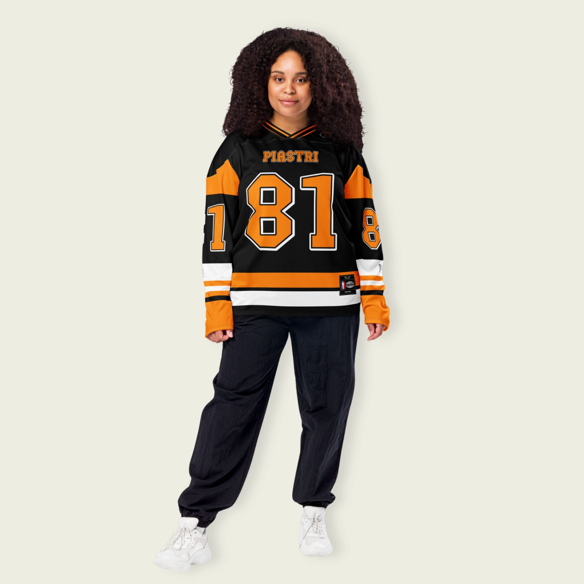 A black hockey jersey with Osacr Piastri's mclaren F1 racing number 81 on the front and back in papaya orange, also the name norris is on the back and front in orange