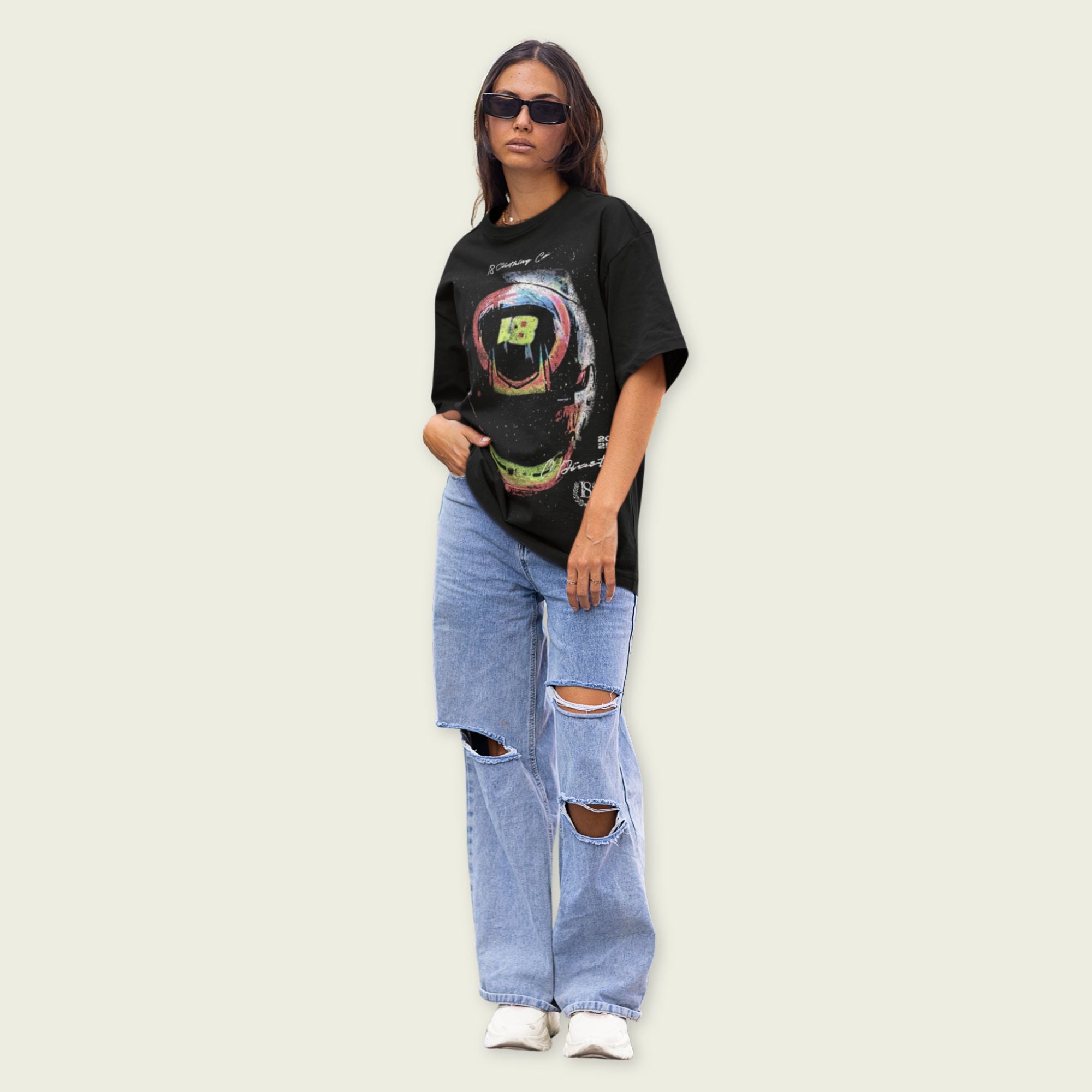 Person wearing a black graphic t-shirt and ripped jeans on a plain background