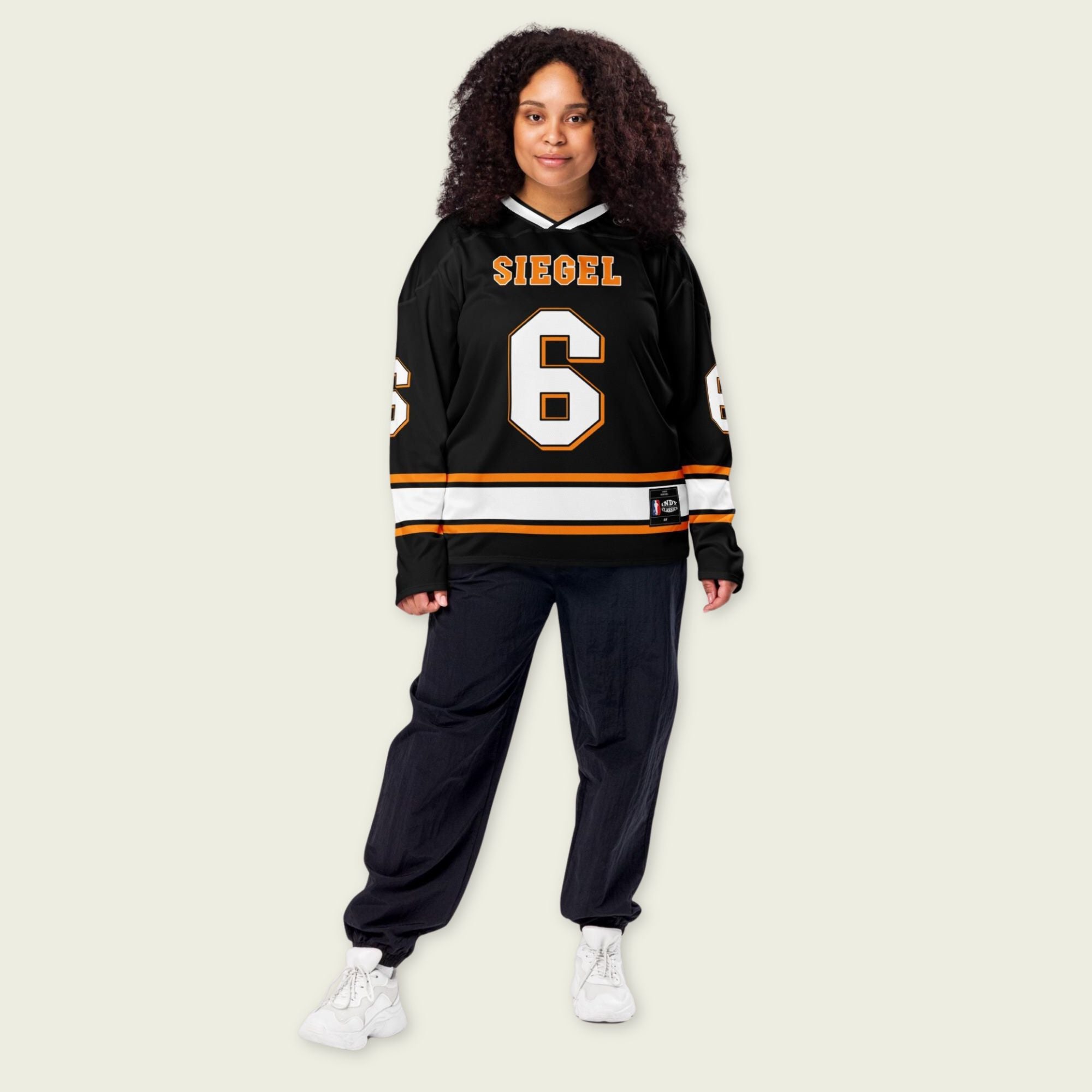 Person wearing a black sports jersey with 'SIEGEL' and number '6' on a beige background