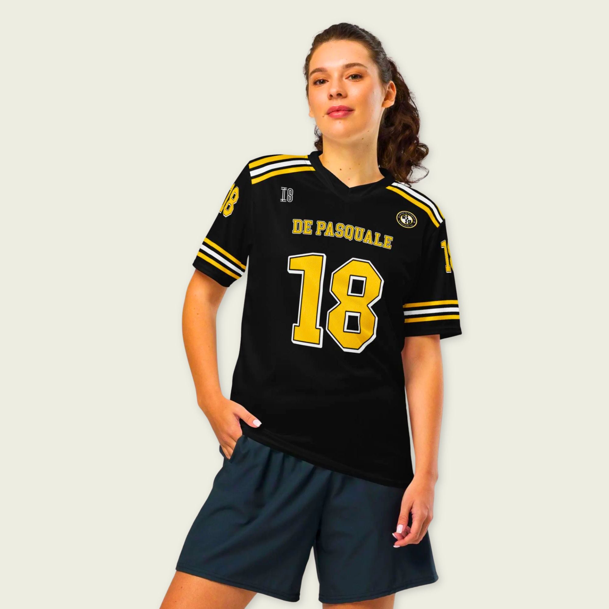 Person wearing a black sports jersey with yellow accents and blue shorts on a plain background