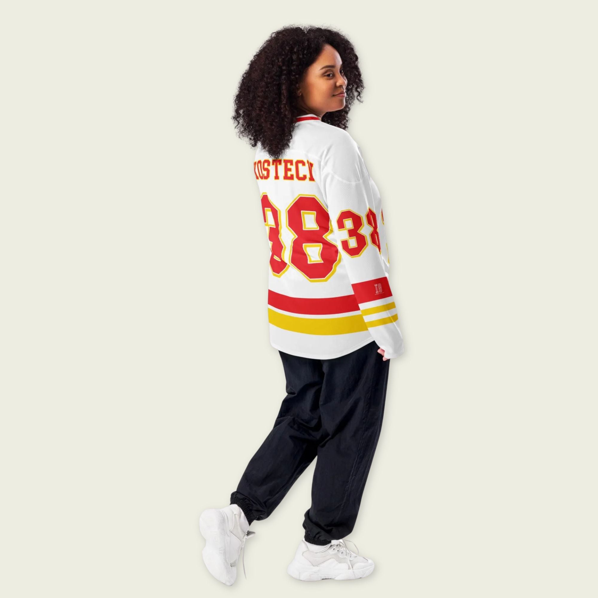 Person wearing a white sweater with red and yellow text on a beige background