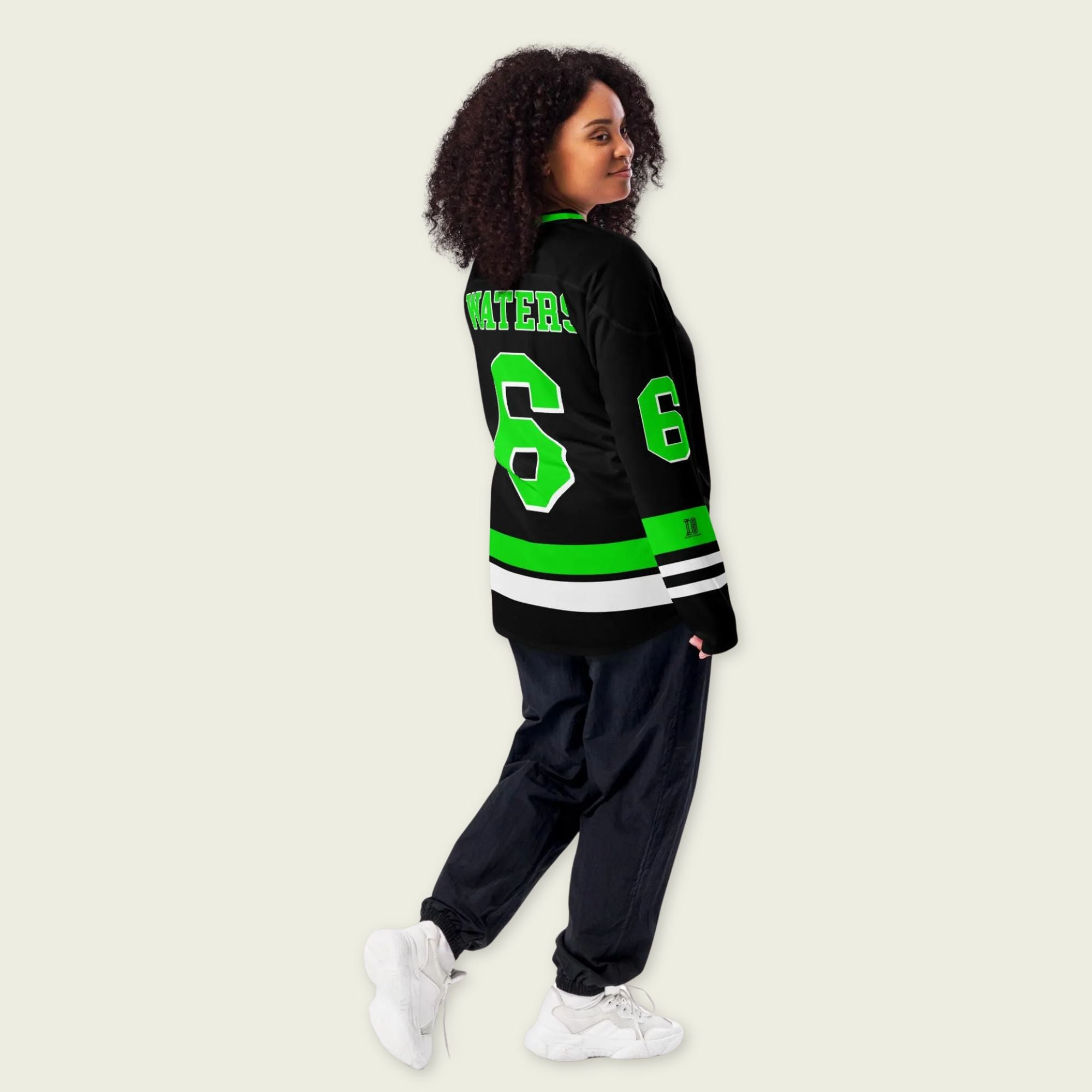 Person wearing a black and green varsity jacket with the number 6 on a beige background