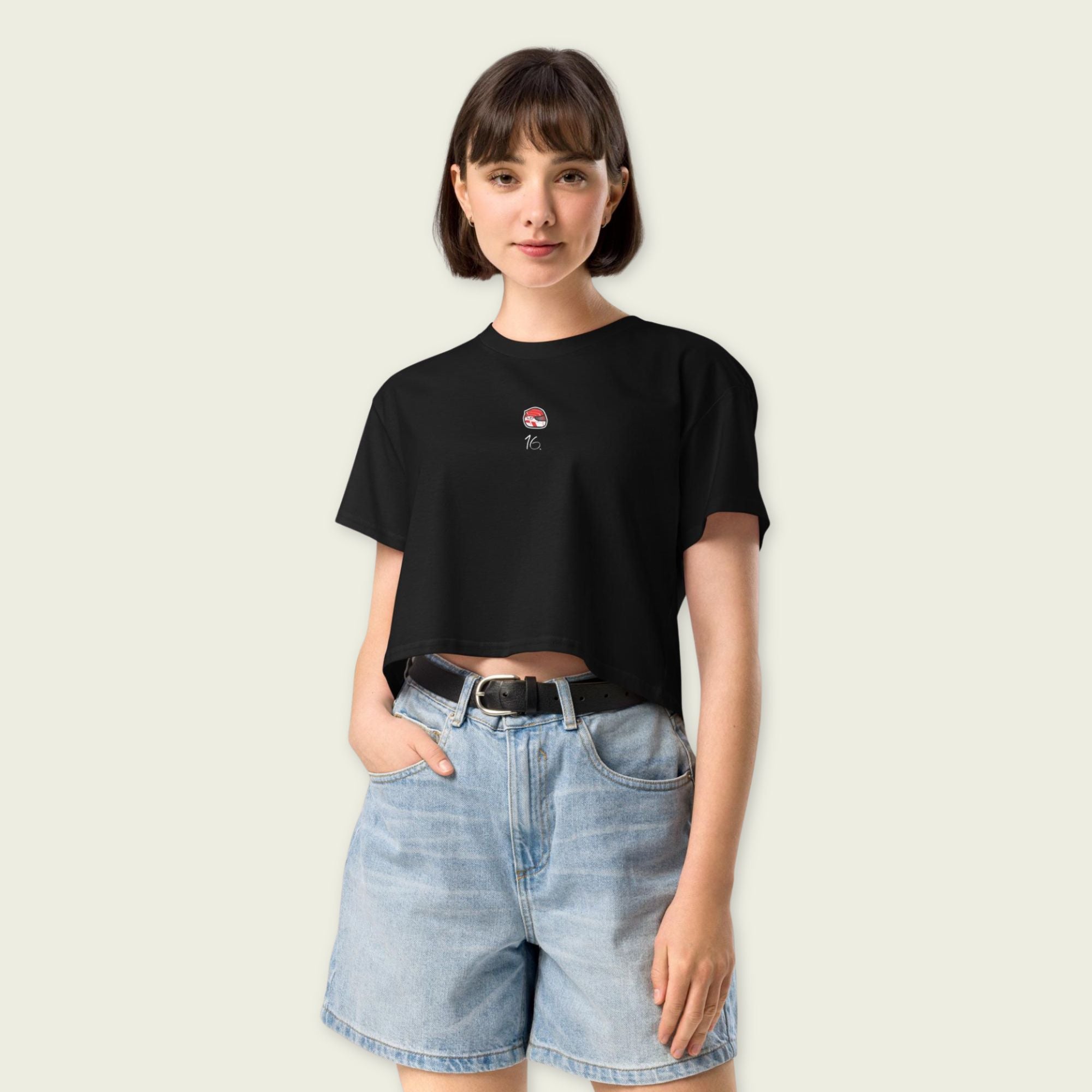 Woman wearing a black t-shirt with a small graphic and light blue denim shorts on a plain background