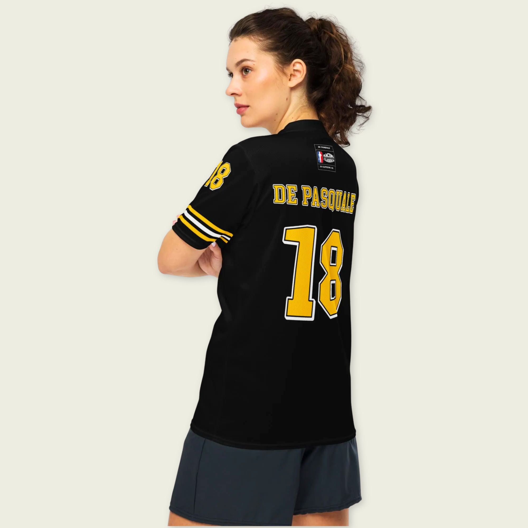 Person wearing a black sports jersey with yellow numbers and text on a plain background
