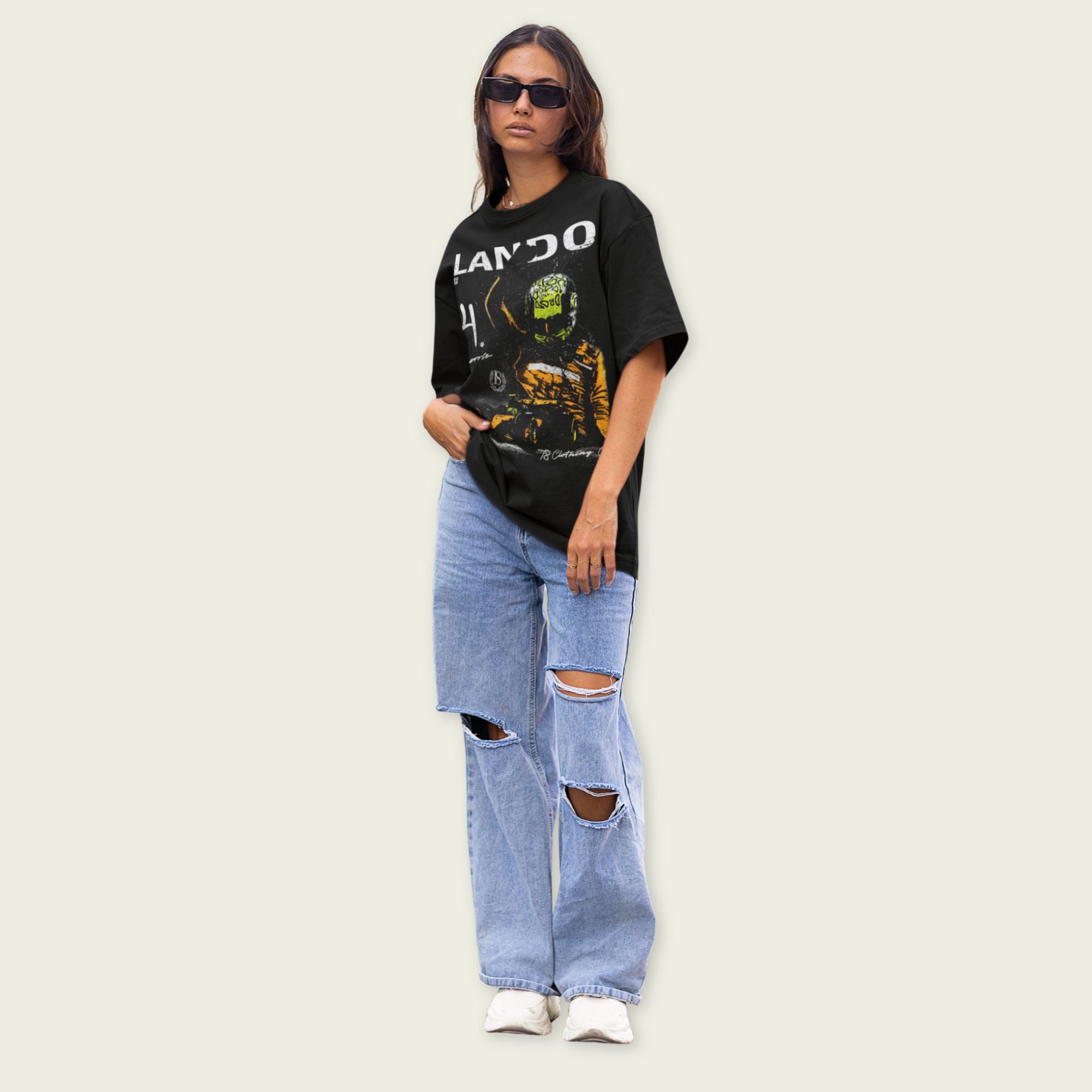 Person wearing a black graphic t-shirt and light blue ripped jeans on a beige background