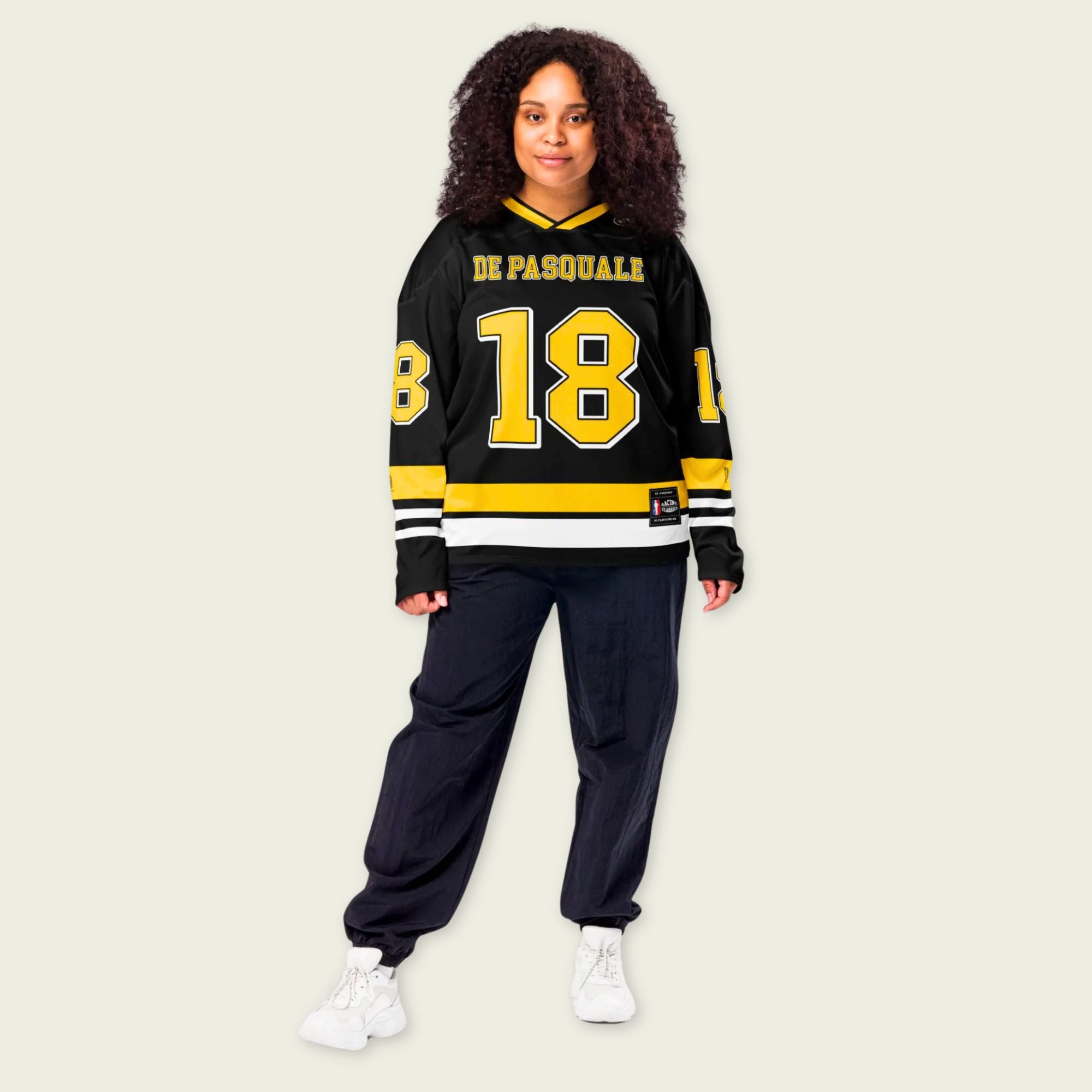 Person wearing a black and yellow sports jersey with the number 18 on a beige background
