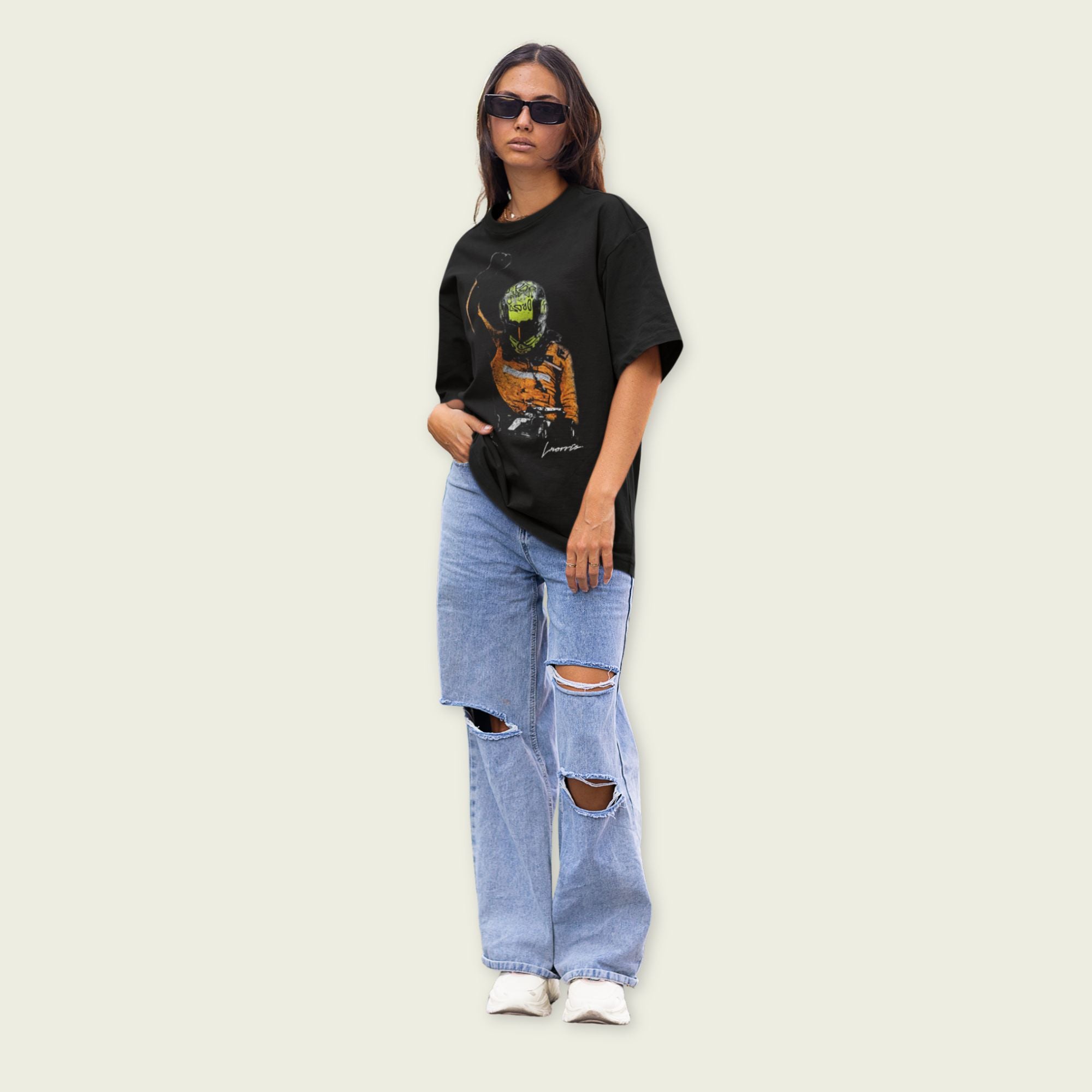 Person wearing a black t-shirt with a graphic design and ripped jeans on a light background