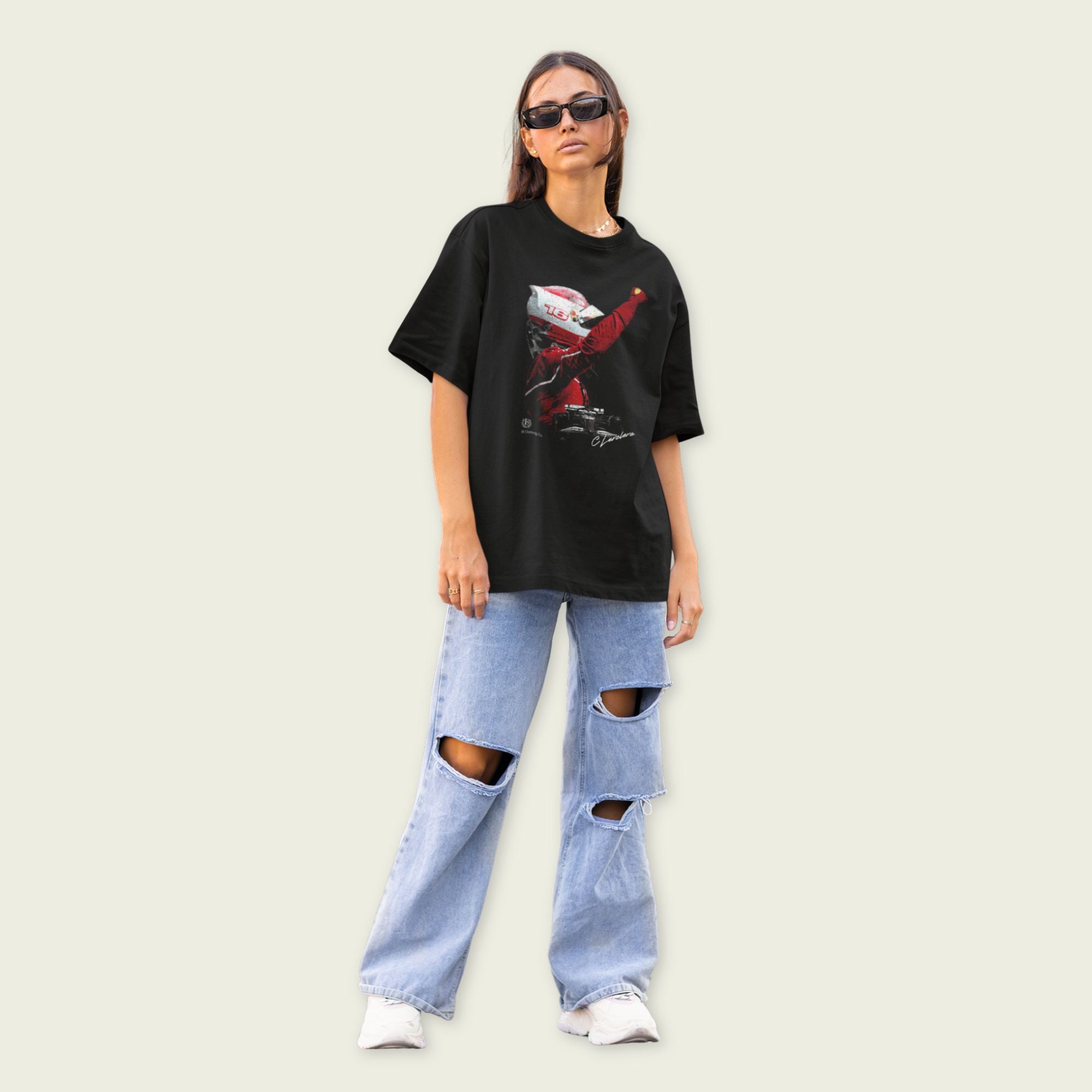 Person wearing a black graphic t-shirt and ripped jeans on a plain background