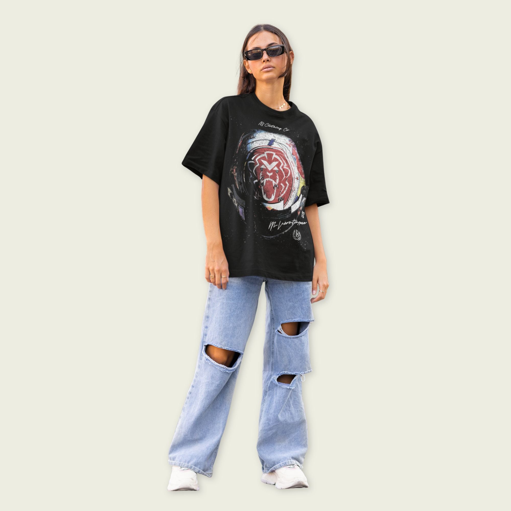 Person wearing a black graphic t-shirt and ripped jeans on a beige background