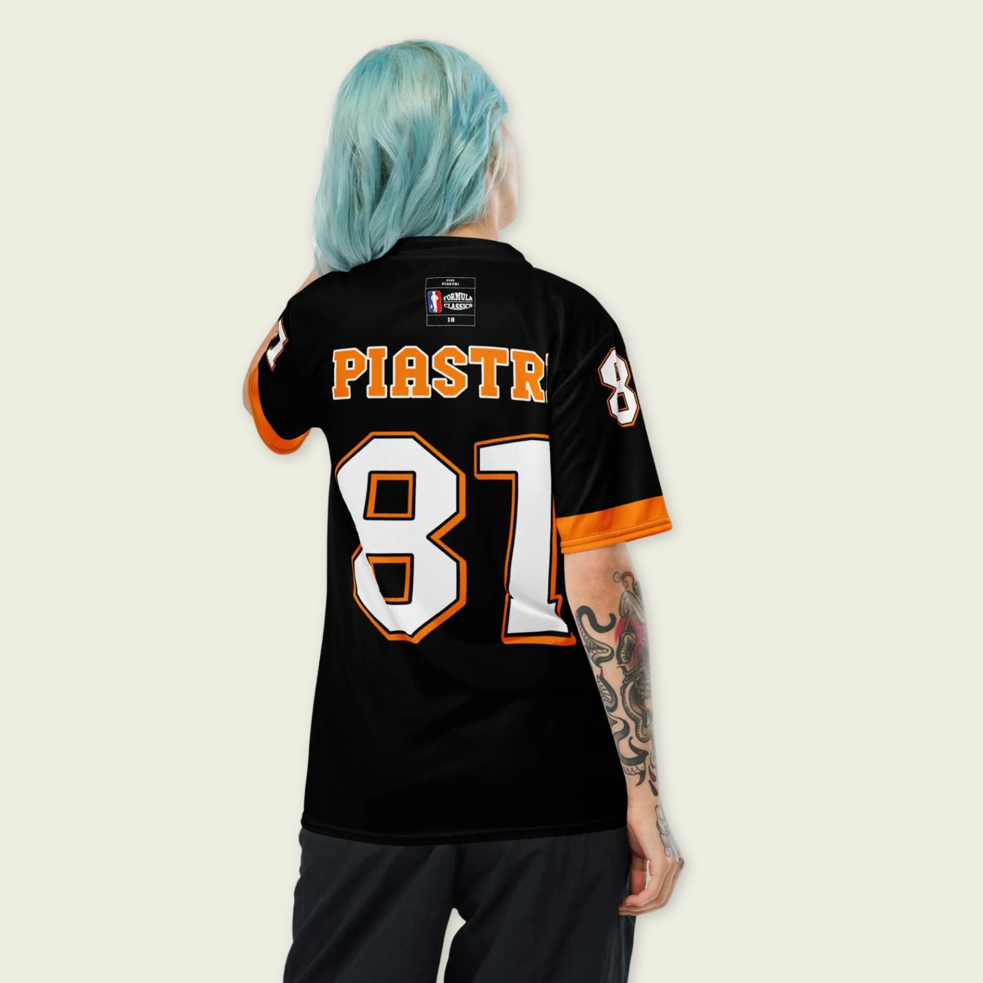 A black and papaya orange football jersey with Oscar Piastri's McLaren F1 racing number 81 on the back and front in white. It has the name Piastri in orange on the front as well.