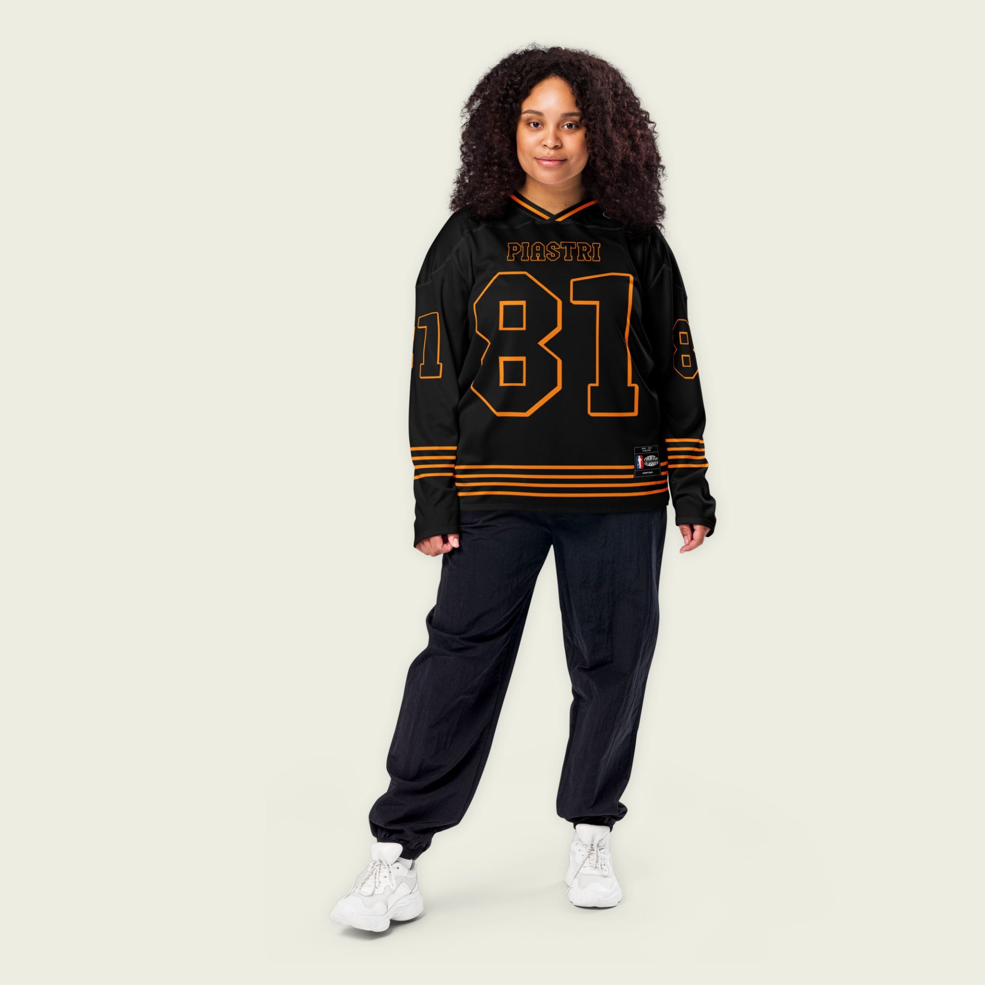 A black ands papaya orange hockey jersey with Oscar Piastri's McLaren F1 racing number 83 in Orange on the front and back. It has the name Piastri the back and front in Orange as well
