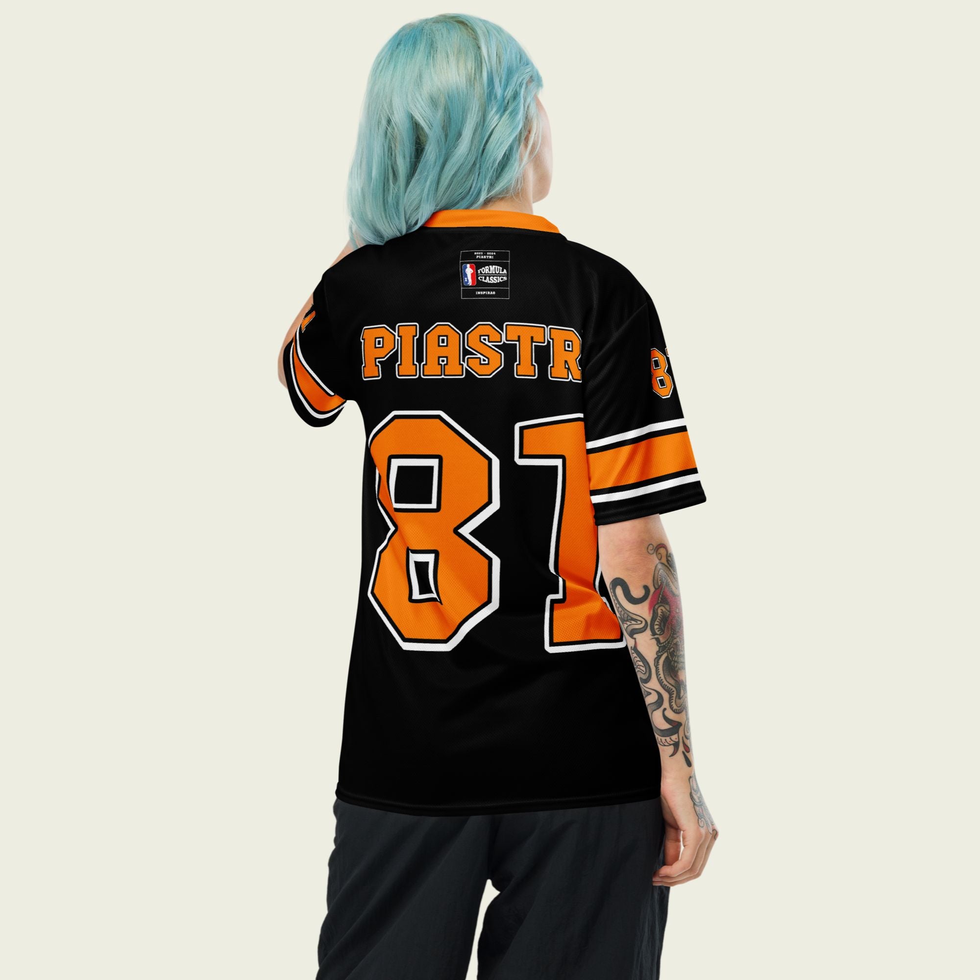 A black and papaya orange football jersey with Oscar Piastri McLaren F1 Racing number 81 in papaya orange on the front and back. The name Piastri is in orange on the front and back.