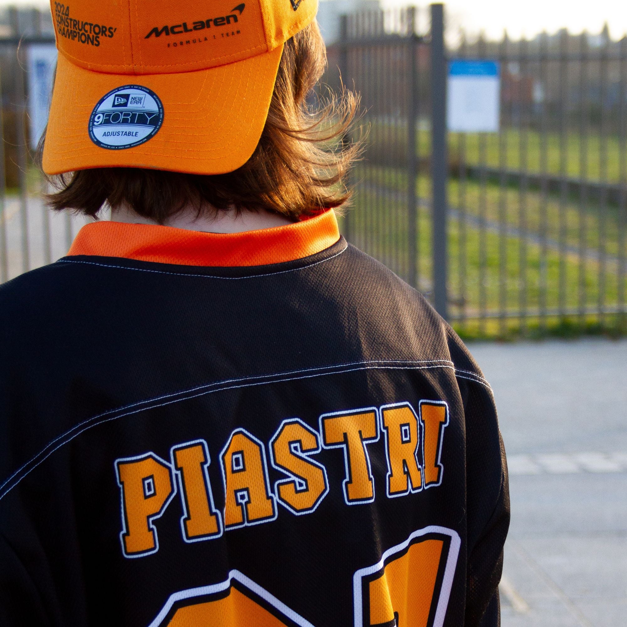 A black hockey jersey with Oscars piastri's McLaren F1 racing number 81 on the front and back in papaya orange, also the name Piastri is on the back in orange