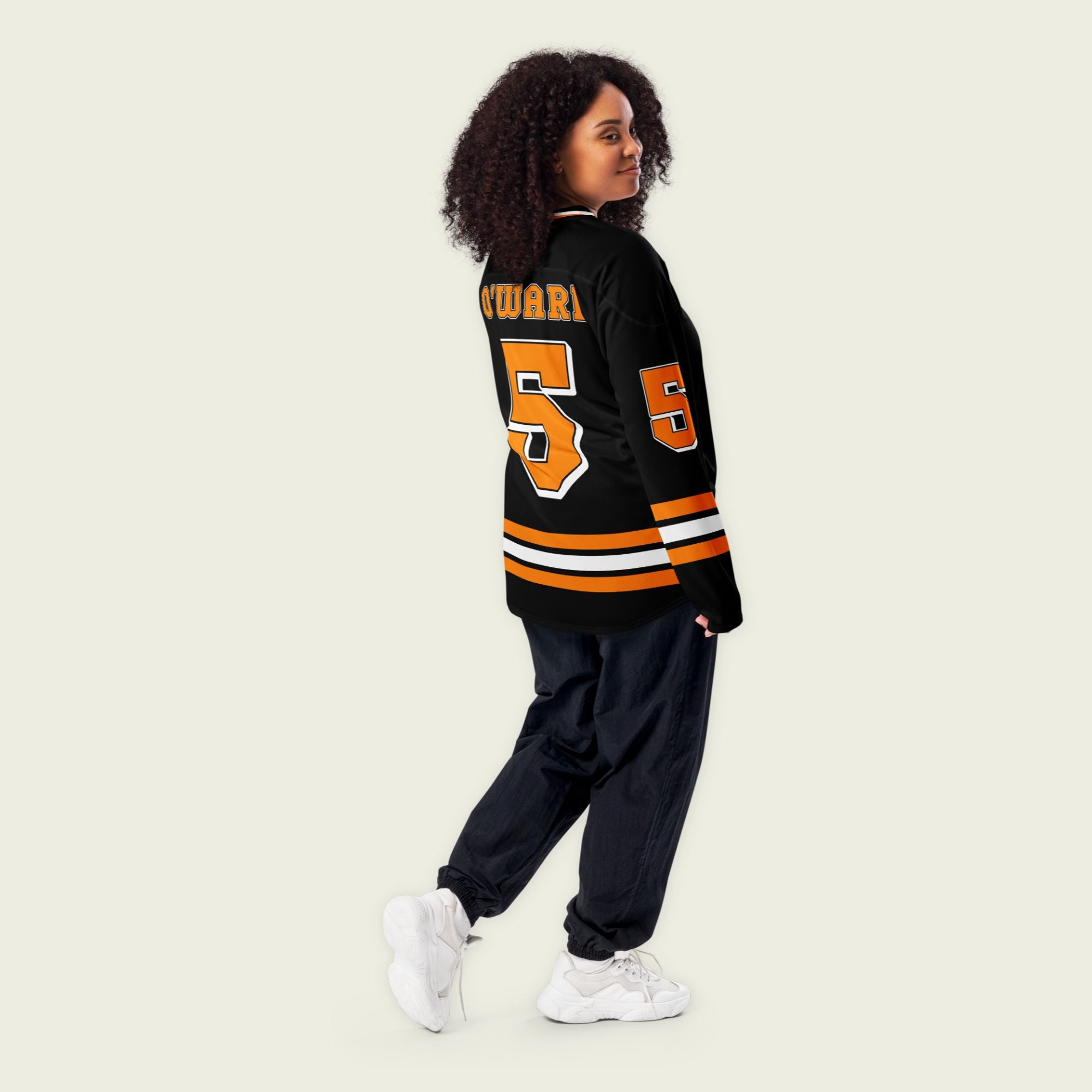 A black hockey jersey with orange papaya stripes. It has Pato O'Wards indycar racing number 5 and the name O'Ward on the front and back in Papaya Orange.