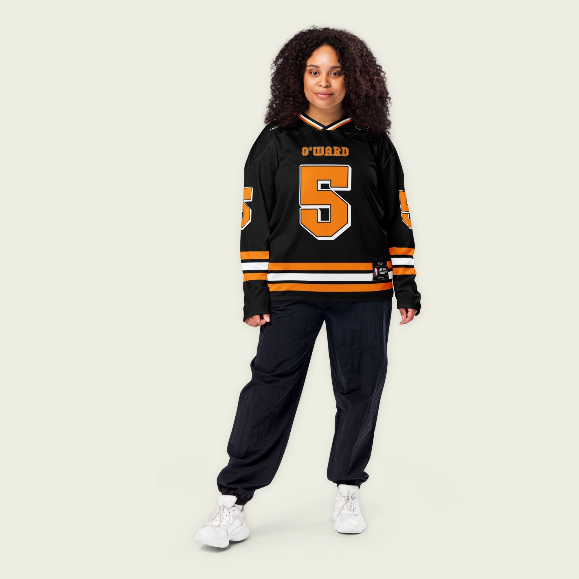A black hockey jersey with orange papaya stripes. It has Pato O'Wards indycar racing number 5 and the name O'Ward on the front and back in Papaya Orange.