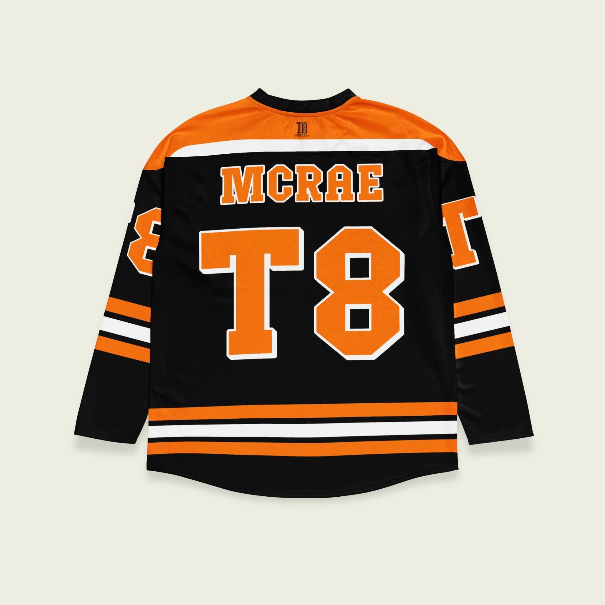 A black, orange, and white hockey jersey with the name Mcrae in orange on the front and back. Also T8 in orange on the front and back.